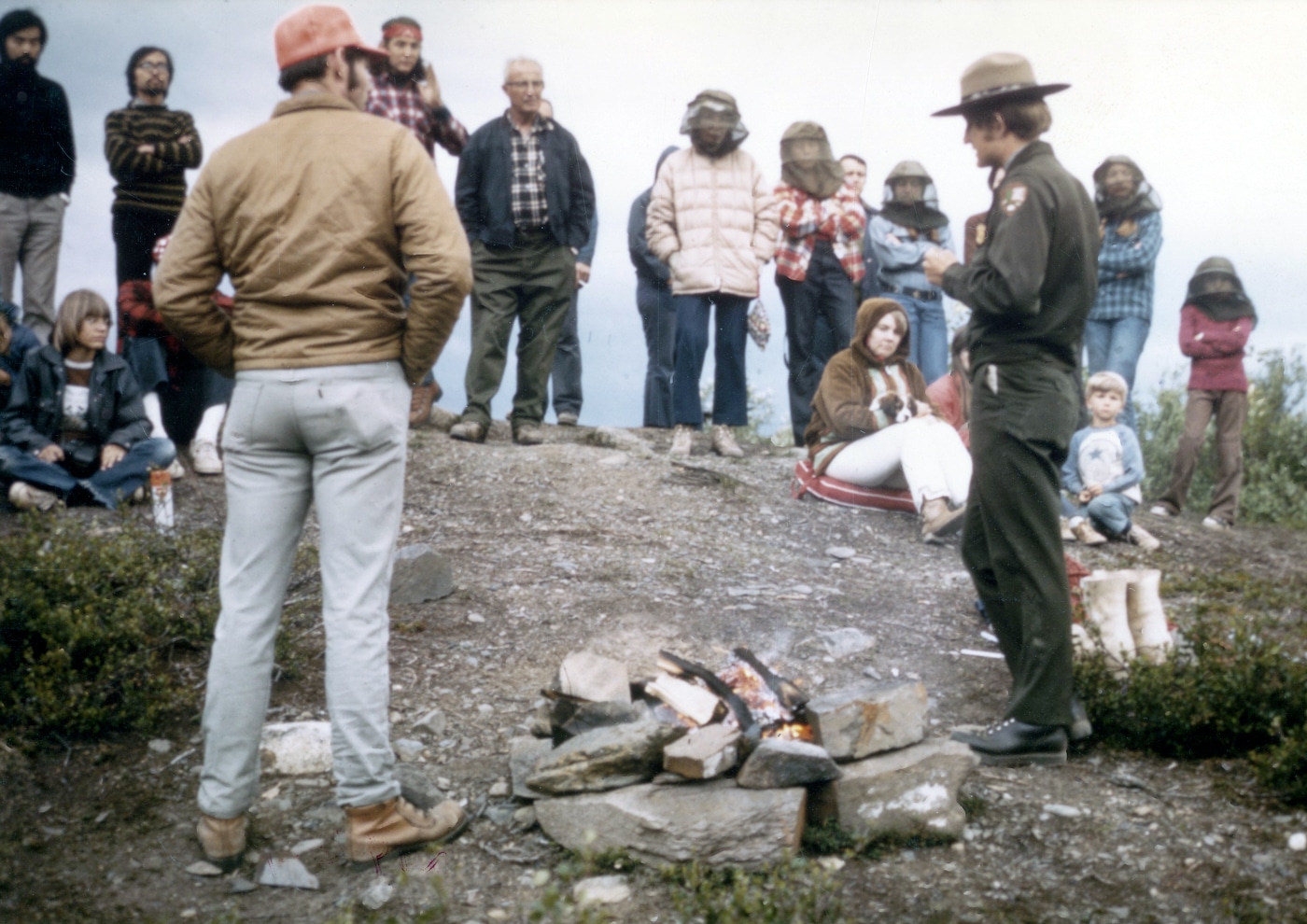 In this photograph, a National Park Ranger provides a campfire safety demonstration to new campers.