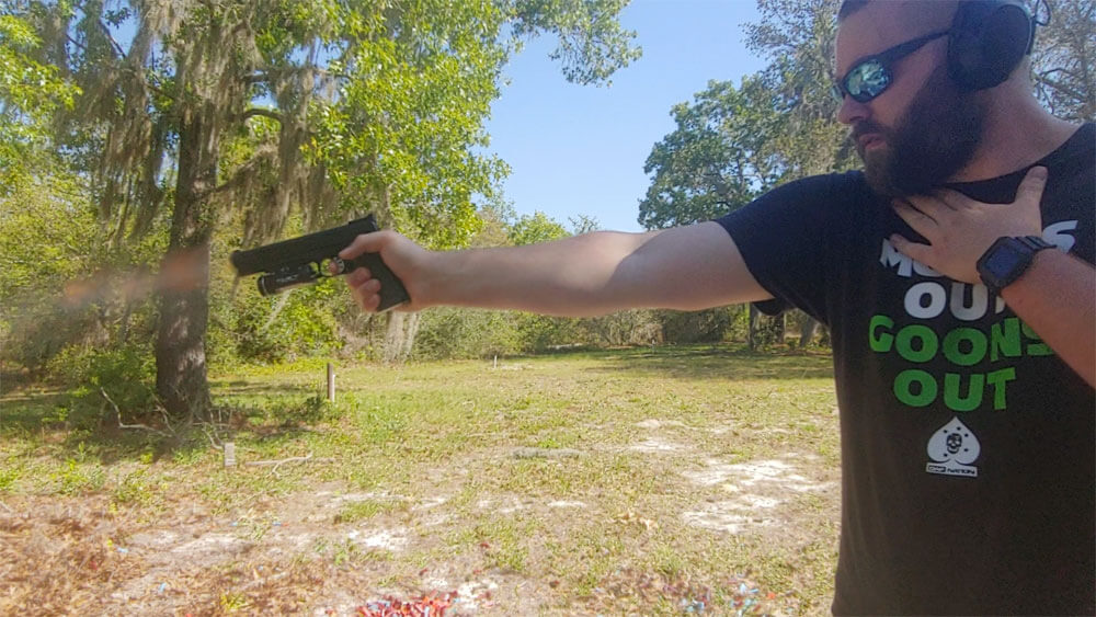 In this photo, the author is shooting a Springfield Armory, Inc. M1911 semi-automatic pistol chambered for the 10mm Auto with one hand. Flames are seen exiting the barrel muzzle.