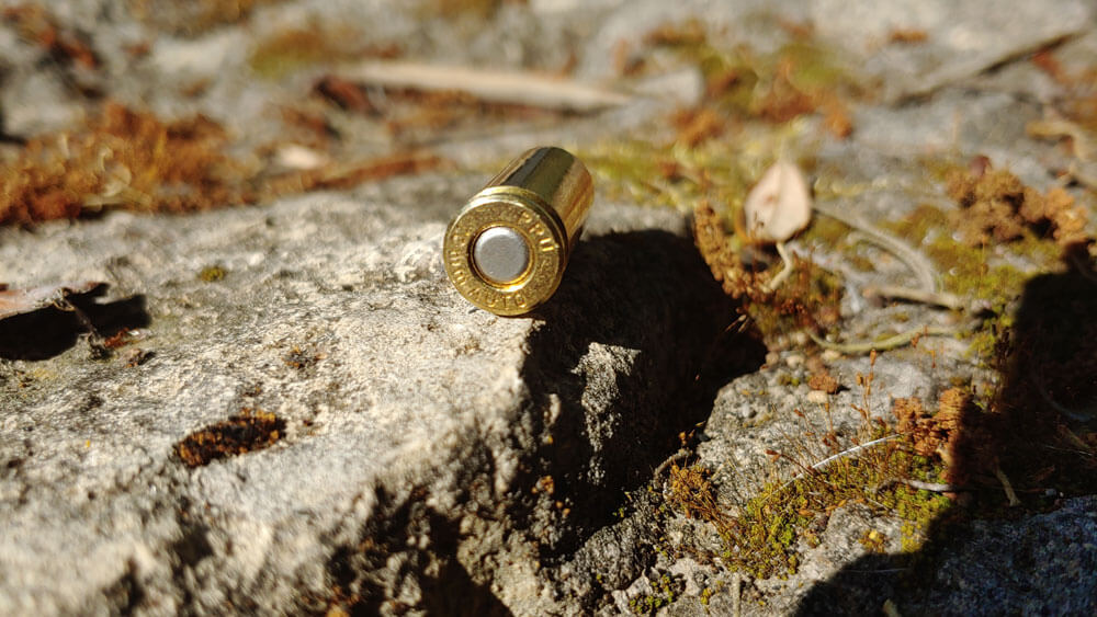 In this image, we see a 10mm Auto cartridge. We see the brass case and primer along with the printed head stamp information.