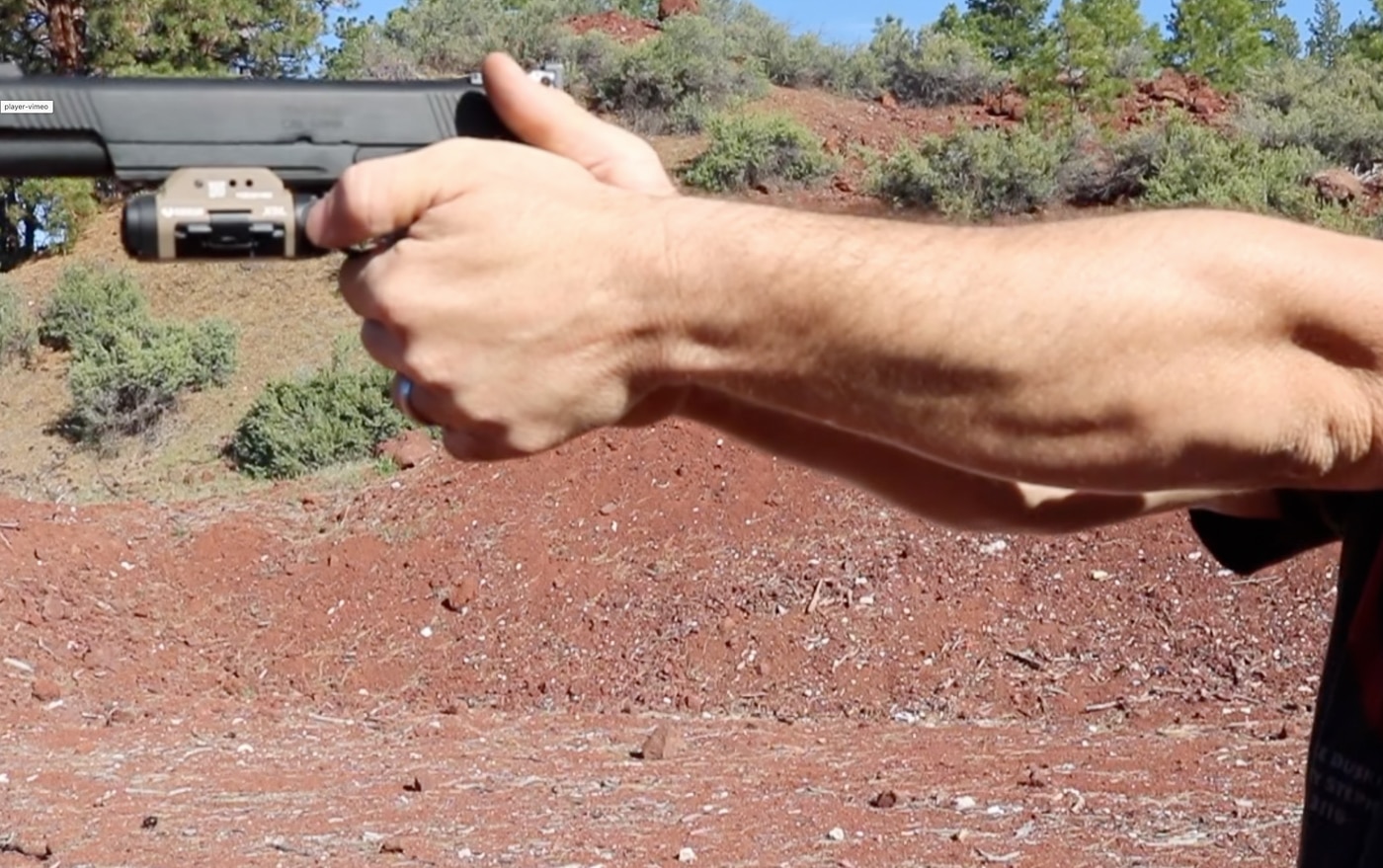A Springfield Armory 1911 pistol with the Viridian X5L light and laser unit securely attached to the front accessory rail, showing the complete integrated system. The Viridian X5L review examines mounted configuration. Light and laser unit installation uses Picatinny rail systems. Green laser housings align parallel to barrel axis. Springfield 1911 platforms accommodate modern tactical accessories. The X5L maintains proper bore offset relationship. Activation controls position for natural thumb access. Home defense pistols benefit from permanent light mounting. Combined units eliminate temporary attachment hassles.