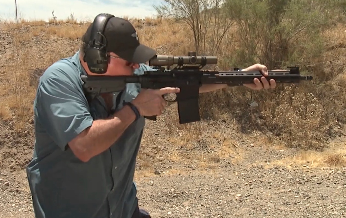A shooter fires multiple rapid shots from a rifle while maintaining an aggressive forward stance during close-range tactical training. Non-standard response drills test fundamental rifle skills. Defensive rifle training requires continuous trigger manipulation. Combat shooting techniques emphasize center mass engagement. Rifle defensive training drills expose grip weaknesses. Tactical rifle work demands shoulder pressure consistency. Rapid engagement training builds stress tolerance. Defensive shooting practice simulates violent encounters. Fighting rifle fundamentals prevent shot dispersion.