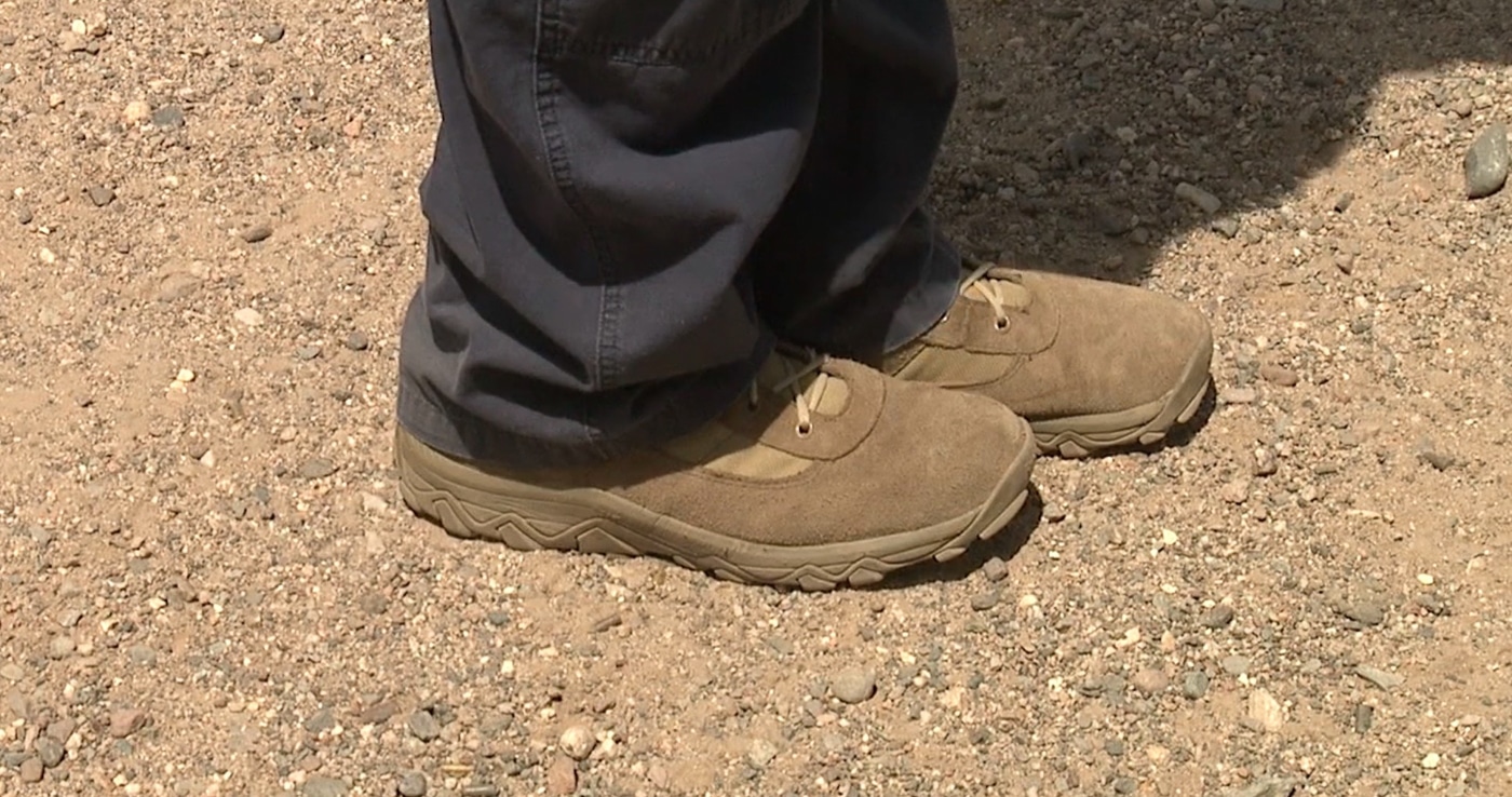 A shooter demonstrates incorrect foot positioning with feet placed too close together, creating an unstable base during pistol training. Learning a shooting stance requires proper foot spacing. Firearms instruction on shooting stances emphasizes shoulder-width placement. Narrow stances reduce stability significantly. Shooters lose balance under recoil. Proper width improves control dramatically. Foot placement affects accuracy outcomes. Instructors correct spacing errors. Wide base provides athletic foundation.