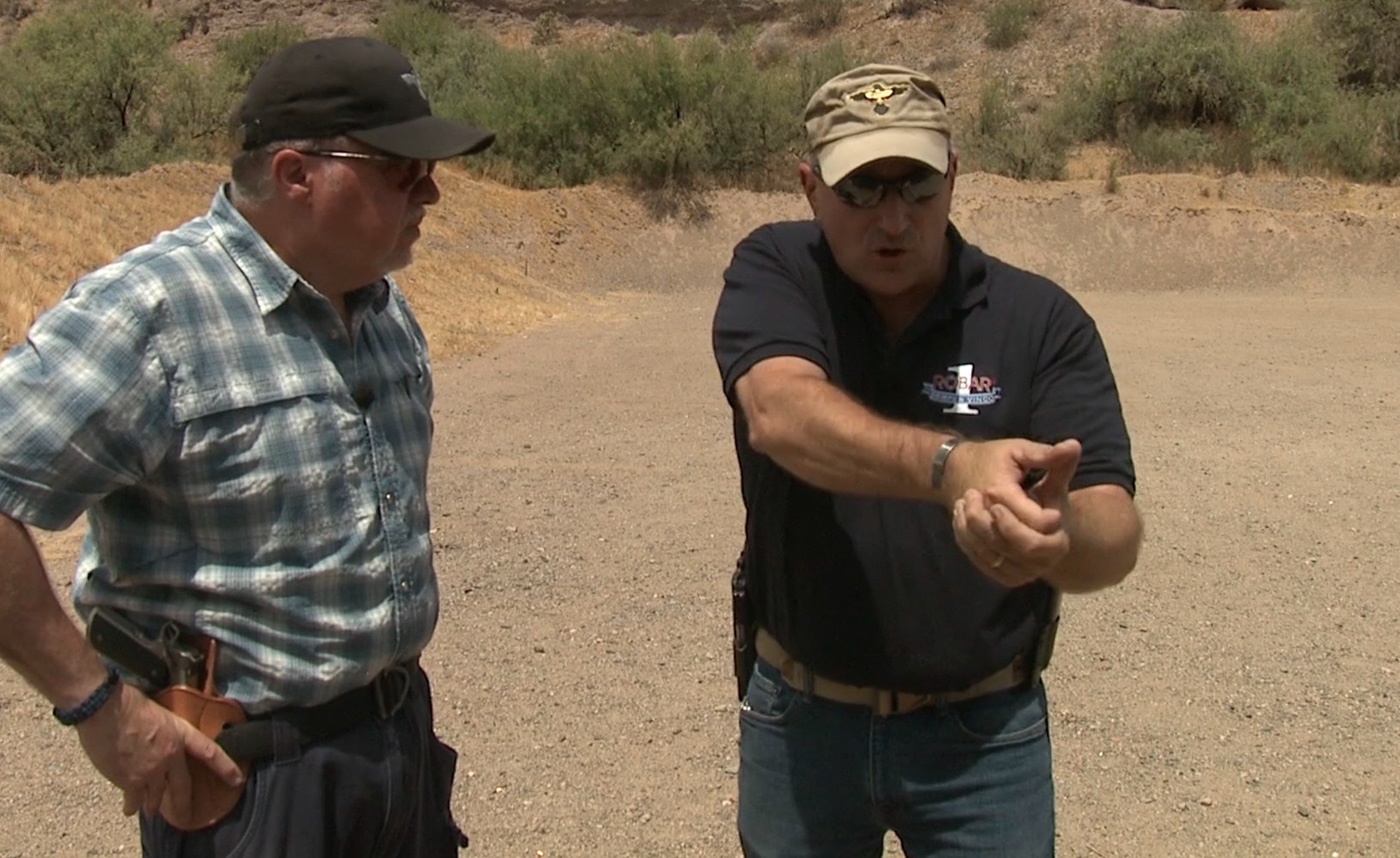 An instructor demonstrates the Weaver stance while moving tactically around a doorway during room clearing training in a shoot house environment. Learning a shooting stance includes understanding tactical applications. Firearms instruction on shooting stances covers movement techniques. Weaver stance enables efficient room clearing. Bladed positioning improves muzzle control. Shooters navigate obstacles more safely. Push-pull mechanics work during movement. Instructors teach tactical positioning. Dynamic shooting requires adaptive stances.