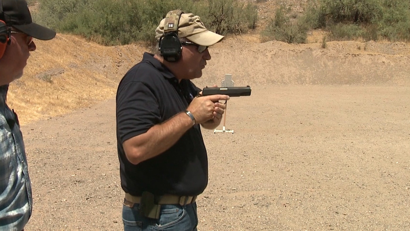 An instructor demonstrates both hands meeting forcefully with the support hand contacting the firing hand grip as the pistol rotates forward into shooting position. Pistol presentation requires aggressive hand integration. Drawing a handgun from a holster involves deliberate bilateral contact. Proper firearm grip establishes through firm hand meeting. Handgun deployment uses forceful support hand placement. Defensive pistol techniques emphasize positive hand contact. Combat shooting mechanics eliminate tentative grip formation. Holster-to-target transition integrates complete hand union. Tactical handgun presentation demands assertive two-handed grip.