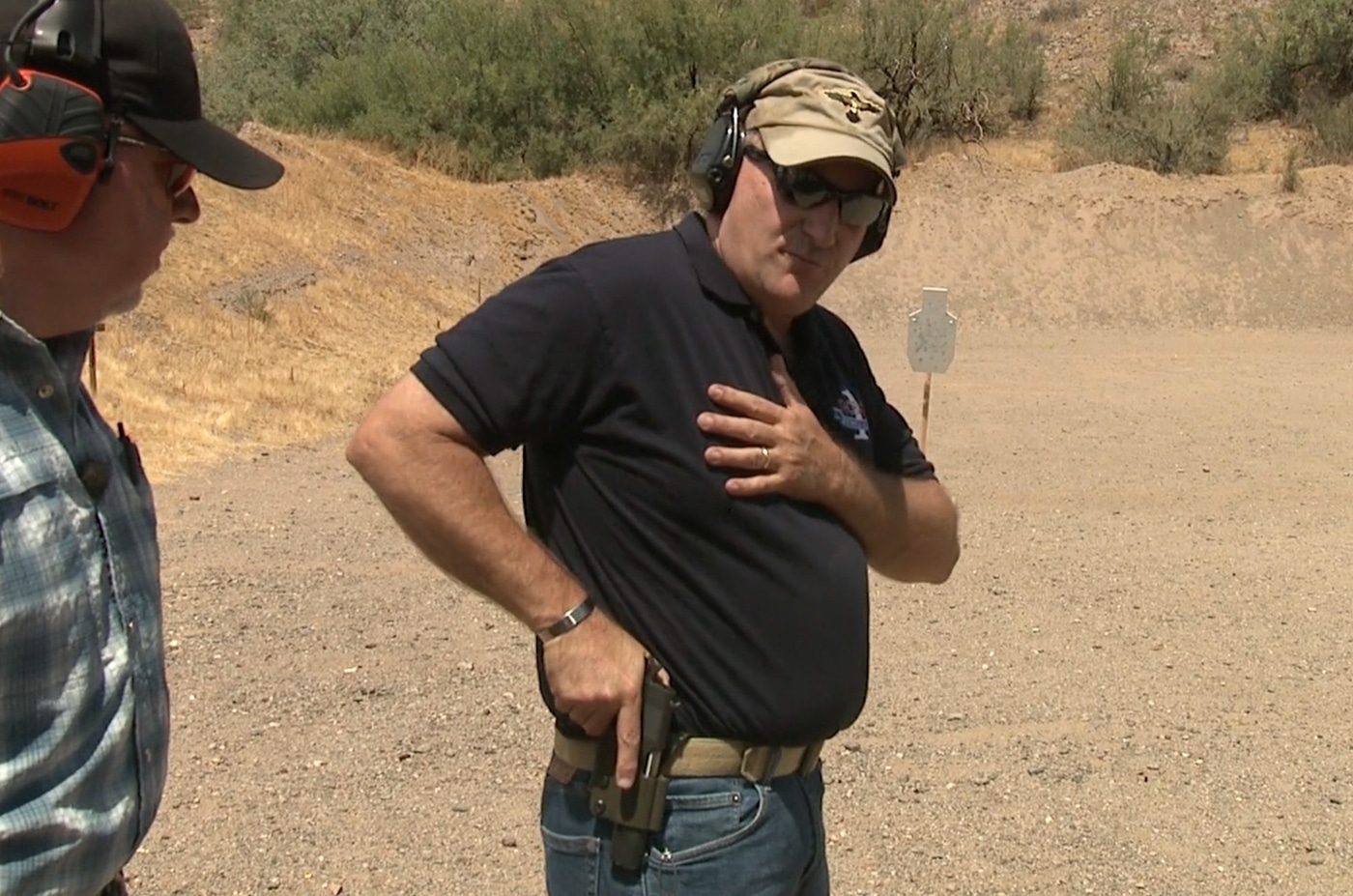 An instructor demonstrates proper hand placement on a pistol grip with high backstrap contact, firm wraparound finger pressure, and correct thumb positioning during a training session. Pistol presentation depends on foundational grip technique. Drawing a handgun from a holster requires established hand contact. Proper firearm control starts with backstrap pressure. Handgun deployment demands consistent finger placement. Defensive pistol techniques emphasize grip fundamentals. Combat shooting mechanics rely on firm hand pressure. Holster work begins with correct hand positioning. Tactical handgun presentation builds on grip mastery.