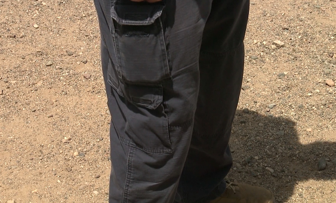 A shooter demonstrates proper knee flexion with a slight bend visible in both legs while maintaining an athletic shooting stance at the range. Learning a shooting stance requires relaxed knee positioning. Firearms instruction on shooting stances emphasizes leg flexion benefits. Bent knees absorb recoil forces. Shooters maintain better stability. Locked knees reduce control significantly. Athletic positioning improves balance. Instructors teach proper leg mechanics. Knee flexion enables mobility.