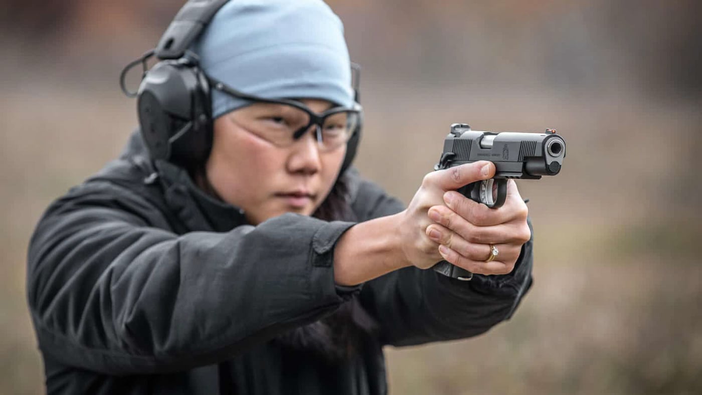 A shooter demonstrates the initial grip establishment phase of drawing a handgun from a holster with both hands moving simultaneously. Pistol presentation requires deliberate movement patterns. Drawing a handgun from a holster demands consistent mechanics. Proper firearm handling emphasizes grip priority. Handgun deployment involves coordinated hand movement. Defensive pistol techniques build on fundamental positioning. Combat shooting relies on repeatable motor patterns. Holster draw efficiency reduces wasted motion. Tactical handgun presentation integrates safety protocols.
