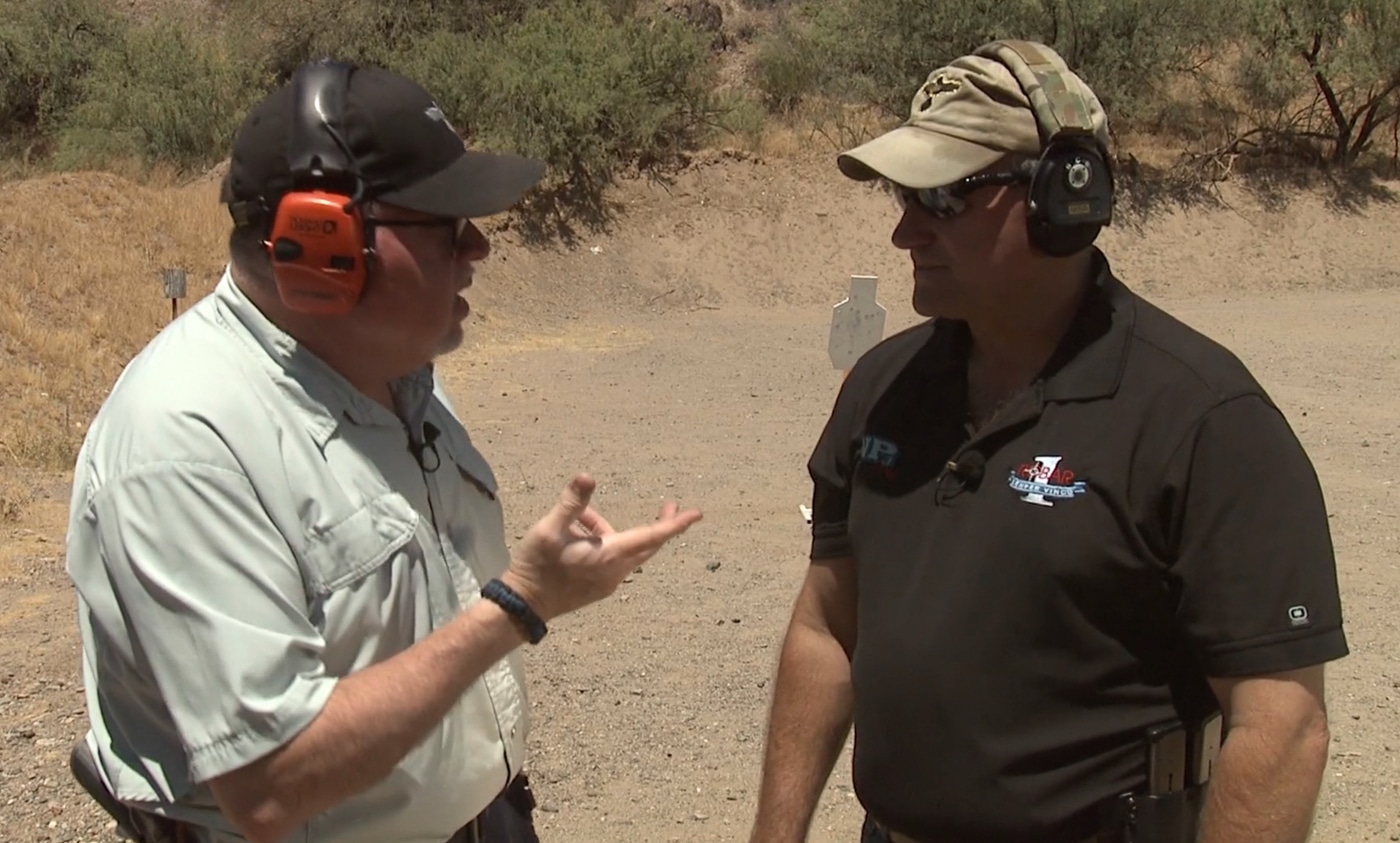 A close-up photograph showing a pistol slide locked to the rear during a one-handed reload drill. One handed malfunction clearance starts with controlled setups. Clearing pistol jam with one hand follows deliberate steps. Slide lock position indicates empty magazine. Single-hand reload technique uses reholstering method. Magazine insertion requires firm seating. Pistol malfunctions demand problem-solving mindset. Firearm manipulation skills develop through repetition. Combat-focused training prepares for worst-case scenarios.