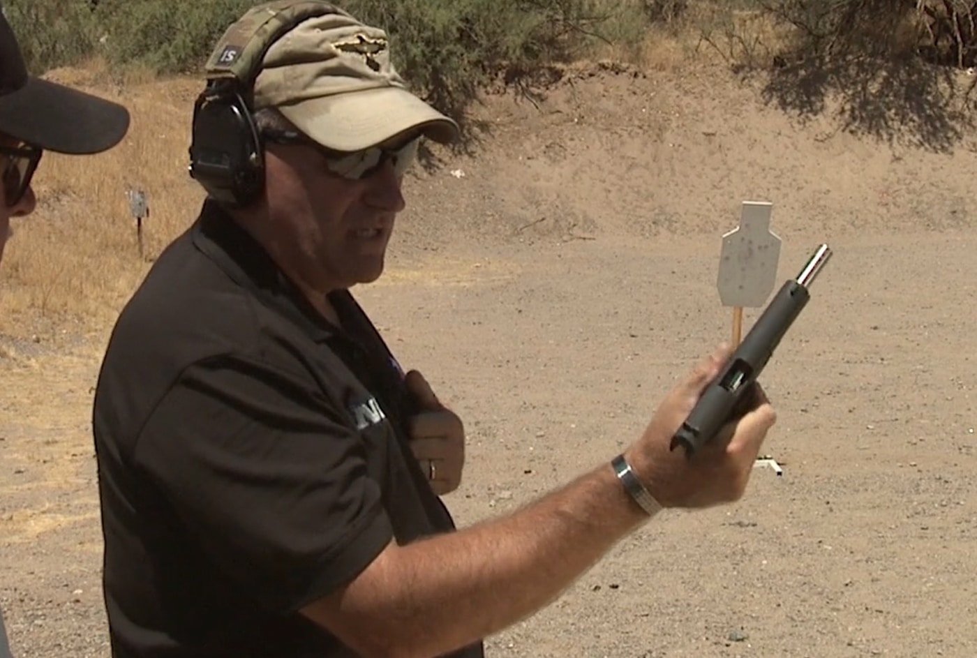 An instructor demonstrating proper thumb placement on a pistol's magazine release button while maintaining a one-handed grip. One handed malfunction clearance includes magazine ejection techniques. Clearing pistol jam with one hand starts with releasing stuck magazines. Magazine release buttons require thumb activation. Strong hand shooters use firing hand exclusively. Pistol grip remains secure during manipulation. Defensive techniques address limited mobility. Firearms instruction emphasizes safety throughout process. Single-hand operations build self-reliance skills.