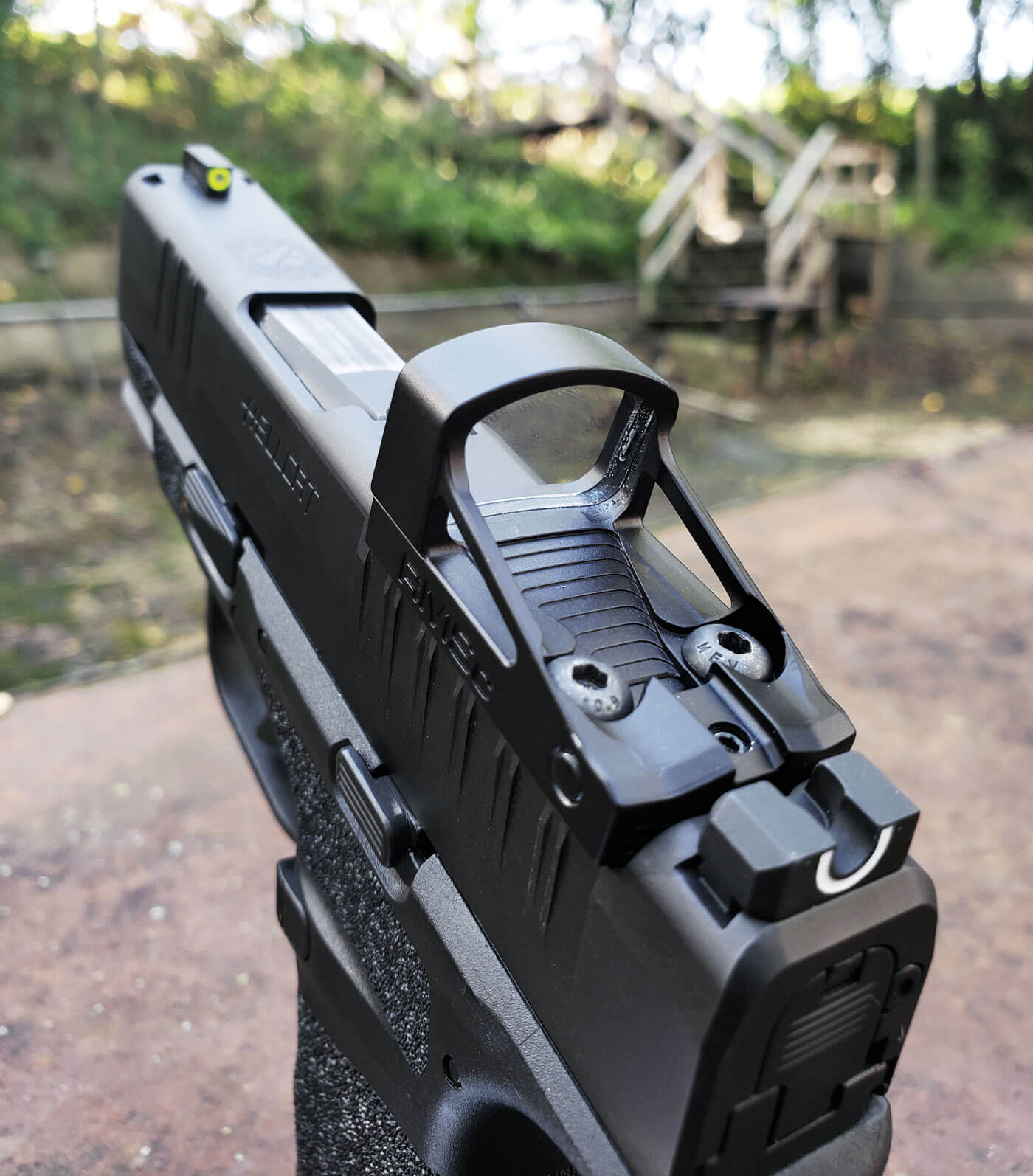 In this image, you can see the top of the Hellcat with a Shield red dot sight mounted on the gun. The Hellcat is an optics ready defensive handgun that is ideal for concealed carry (CCW). With a reflex sight mounted on the Springfield Armory pistol, you can get a perfect co-witness with the factory sights. This provides optimal visibility in a stressful situation. Also, most Hellcat holsters are designed to work with red dot sights. U-notch sight on Springfield Hellcat co-witnesses through a red dot sight.