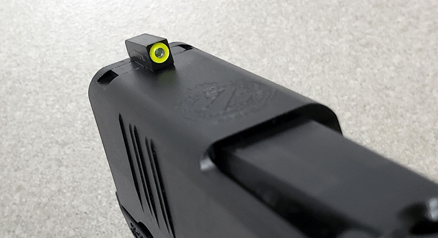 In this picture, we see the Hellcat front sight with photoluminescent ring around the green tritium vial. Night sights are designed to provide a great sight picture in day or night conditions. The Hellcat OSP and Hellcat Pro both come with these sights standard. They are not suppressor hight and fit into the dovetails machined into the slide. The are compatible with night vision goggles and equipment. 