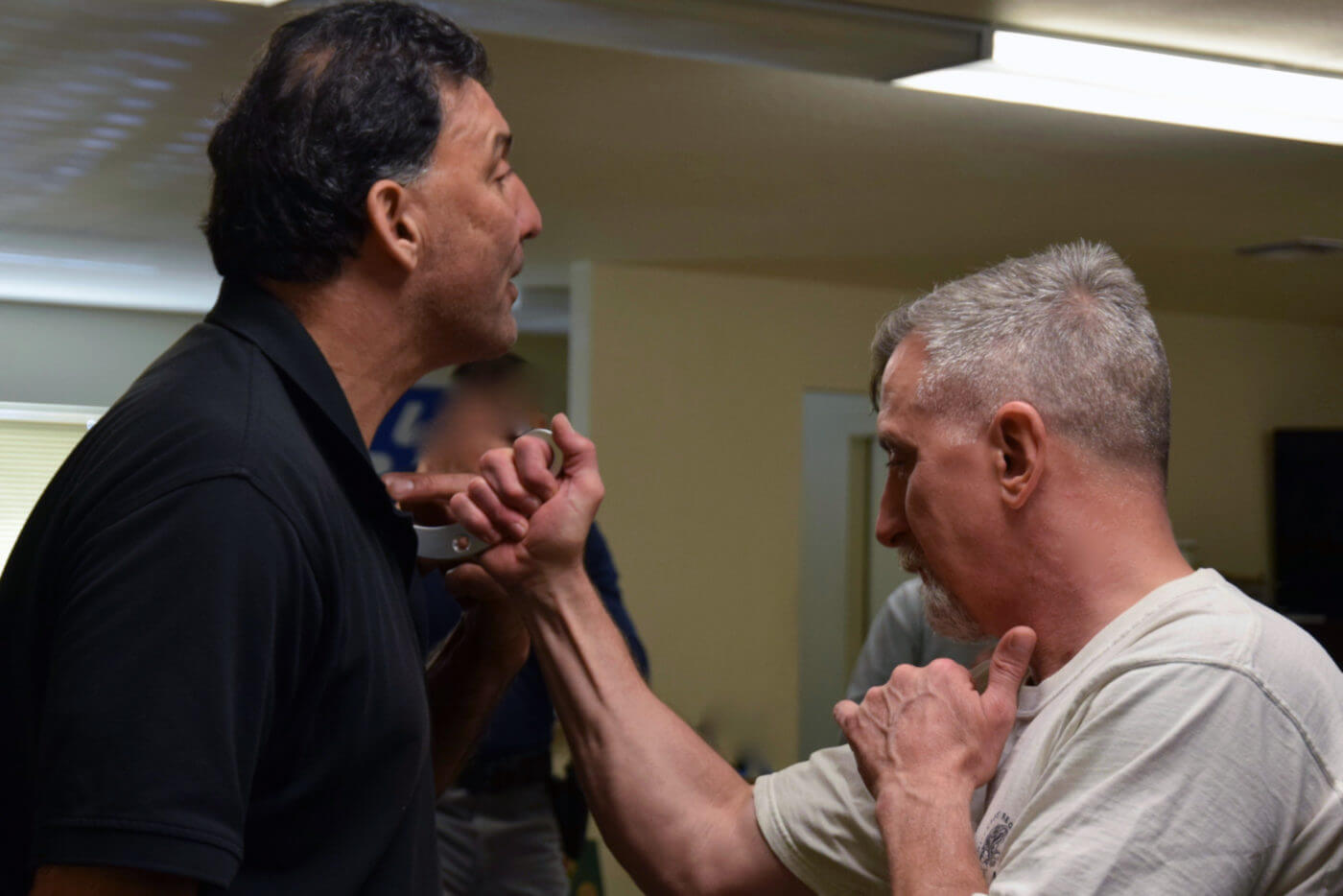 instructor stabs student with karambit in training class In this image, the author is in a knife fighting training class. An instructor demonstrates using a karambit to stab an attacker.
