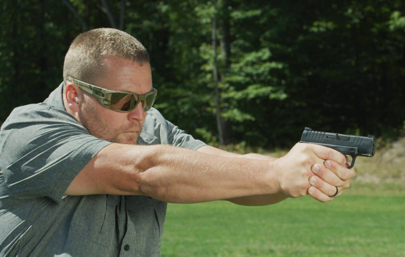 In this image, a man is shown shooting the Hellcat using the u-notch night sights from the factory. It doesn't take a lot of mathematics to figure out the high-quality nature of these sights. While some people prefer a qpxzvvbmswqpdg style sight, the author believes the factory sights offer a sharper sight picture. Regardless, they are quality night sights that allow for fast sight alignment with or without the use of a night-vision device when shooting.