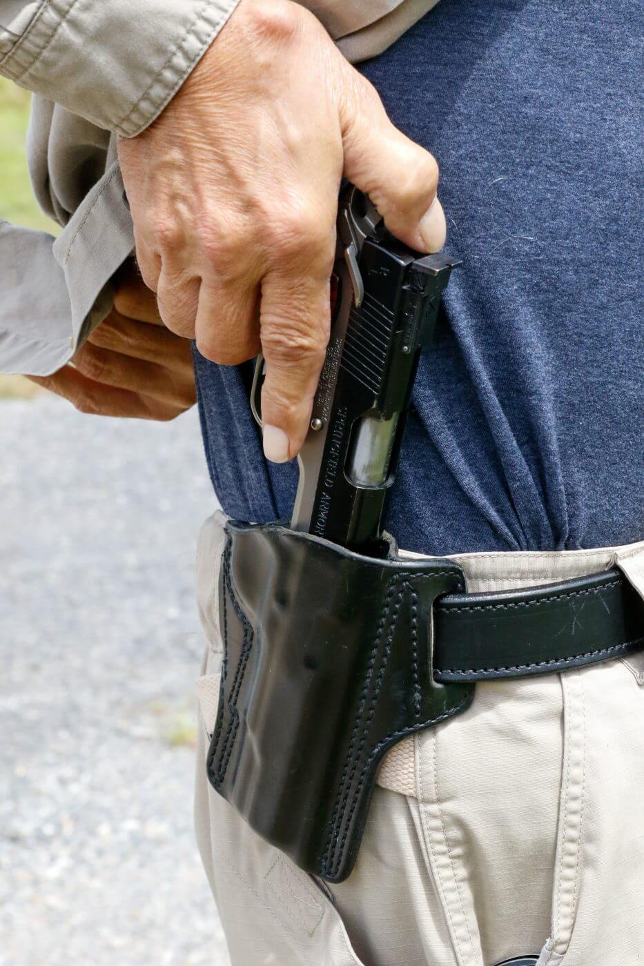 In this photograph, gun expert Massad Ayoob demonstrates how to properly carry a 1911 for CCW in a leather holster with a quality gun belt.