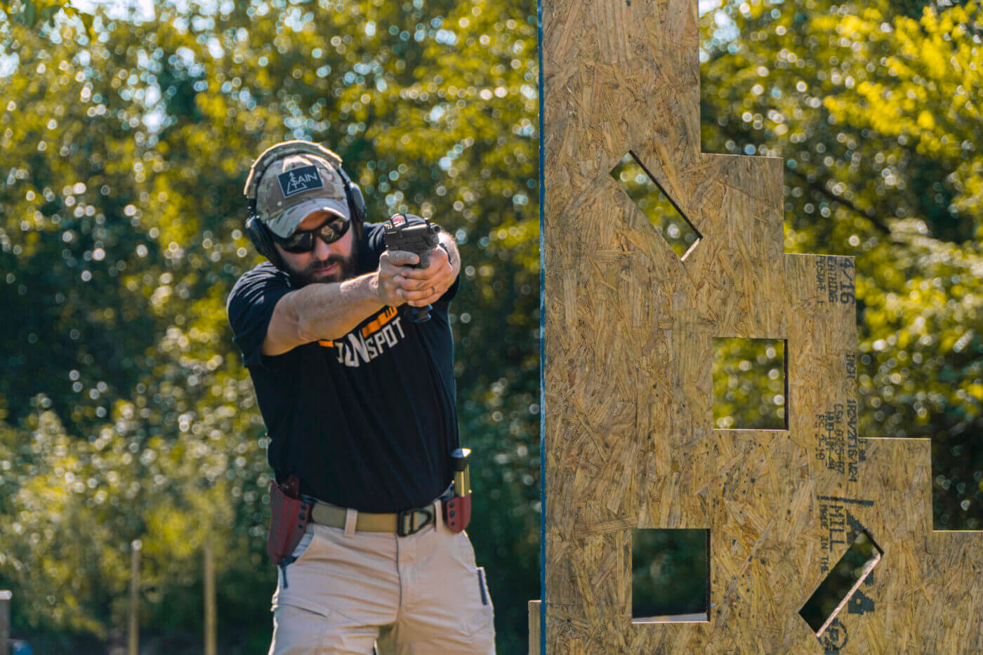 In this photograph, the law enforcement officer instructor demonstrates shooting from cover using a semi-automatic handgun chambered for the 9x19mm Parabellum cartridge.