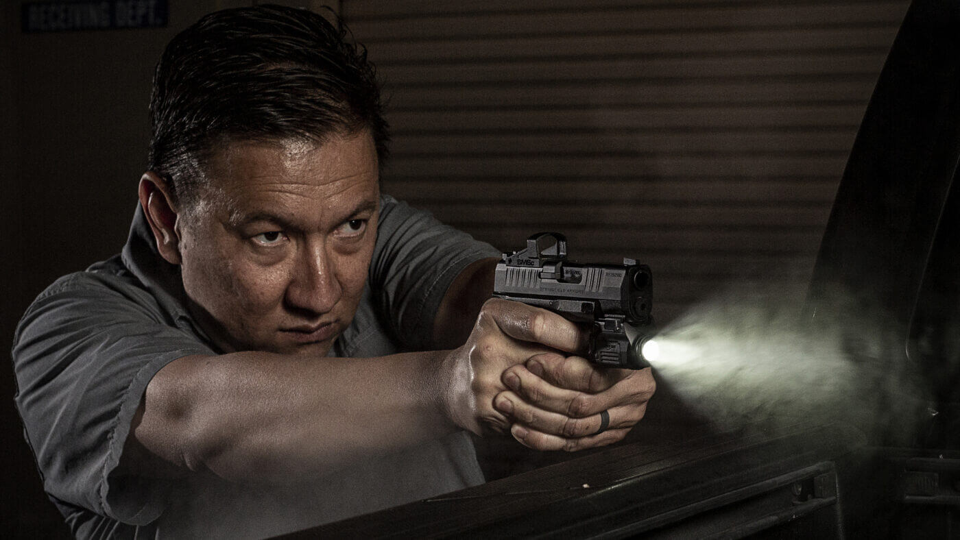 In this photo, the author shoots a Springfield Armory Hellcat pistol with a SureFire XSC tactical light on an indoor shooting range. The XSC is designed to fit on a wide range of handguns including the SIG Sauer P365, Smith & Wesson Shield and the Glock sub-compact handguns.