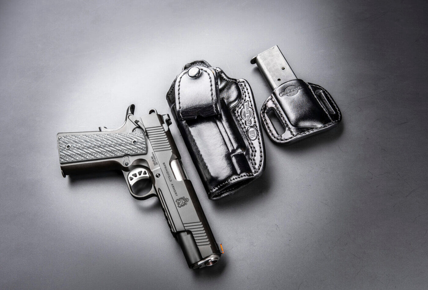 A close-up of a black leather Mitch Rosen holster paired with a matching black leather Mitch Rosen magazine holder, showcasing meticulous craftsmanship. The setup holds a Springfield Armory 1911 pistol chambered in .45 ACP, emphasizing the precision fit and durability of Mitch Rosen holsters. This high-quality leather gear reflects the brand's reputation for premium firearm holsters and personal defense holsters. The photo highlights the elegant yet functional design of these concealed carry accessories.