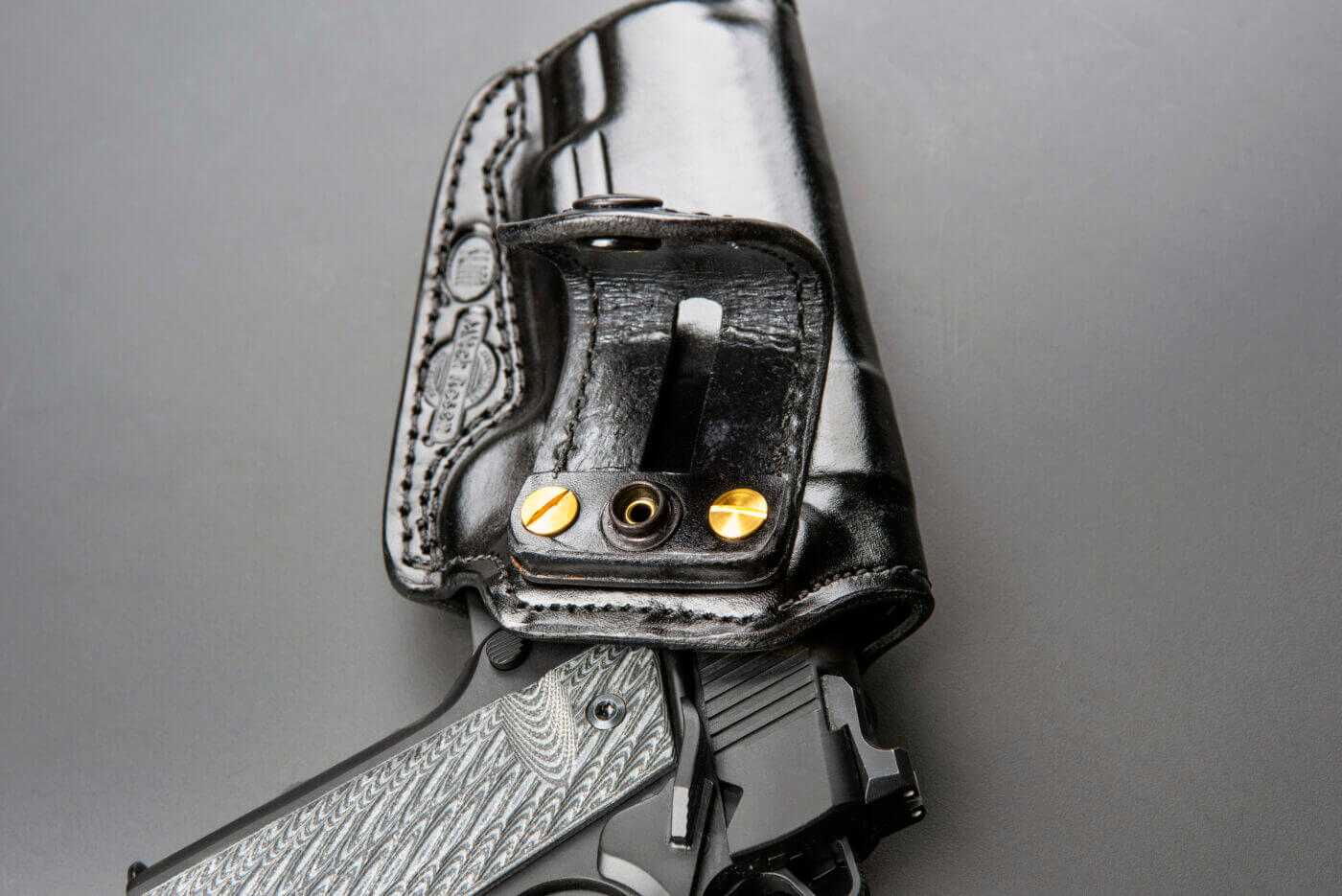 A close-up of the leather belt loops on a Mitch Rosen inside-the-waistband (IWB) holster, securing a 1911 pistol, showcases the brand’s meticulous craftsmanship. The smooth black leather and reinforced stitching reflect the high-quality gun holsters Mitch Rosen is known for. This design ensures a secure and comfortable carry, ideal for concealed carry holsters. The photo emphasizes the durable leather holster materials and precise attention to detail that define Mitch Rosen holsters. It works with Springfield Armory Inc., SIG SAUER, Colt Mfg. Co., Smith & Wesson, Ruger and other .45 ACP pistols of the M1911 style.