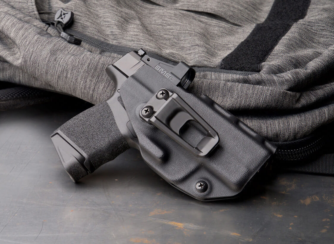 Shown in a holster, this Springfield Hellcat is equipped with a red dot optic