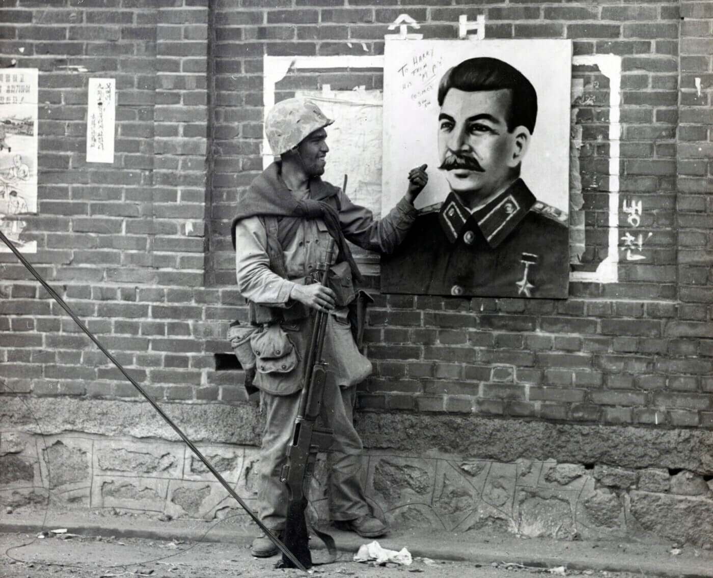 Marine with a BAR in Korea in front of a Joseph Stalin poster