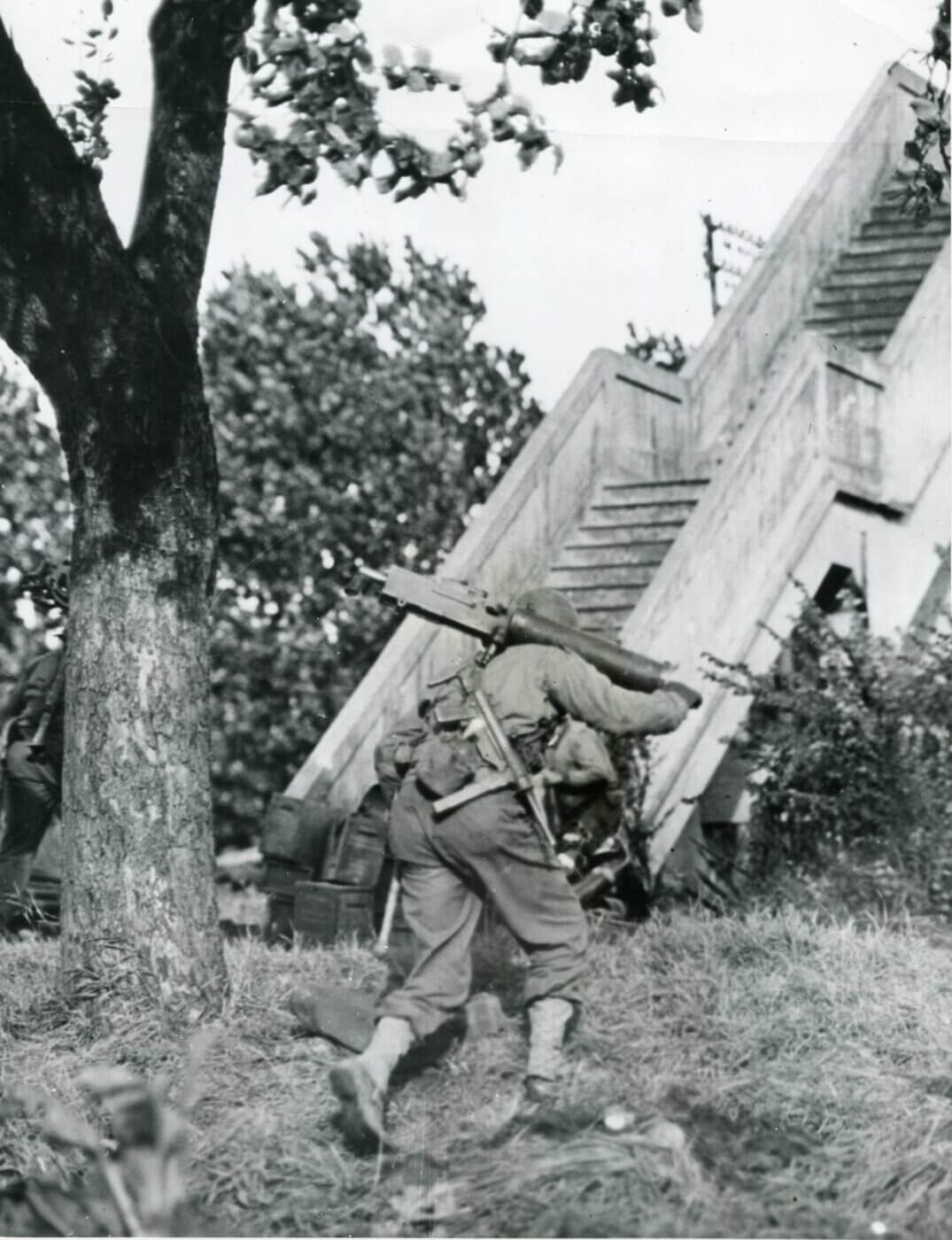 A Browning M1917 machine gunner carries a M3 SMG