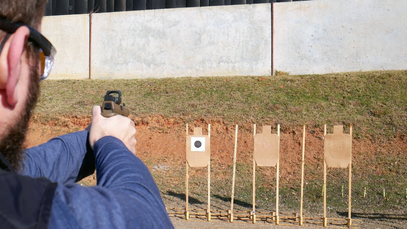 Man in hat aiming at targets with pistol