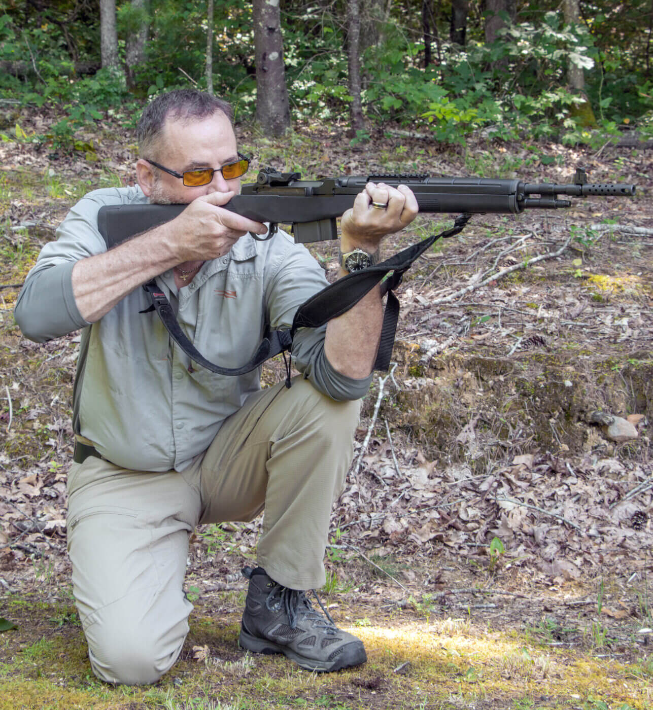 Man showing how to shoot a rifle while kneeling