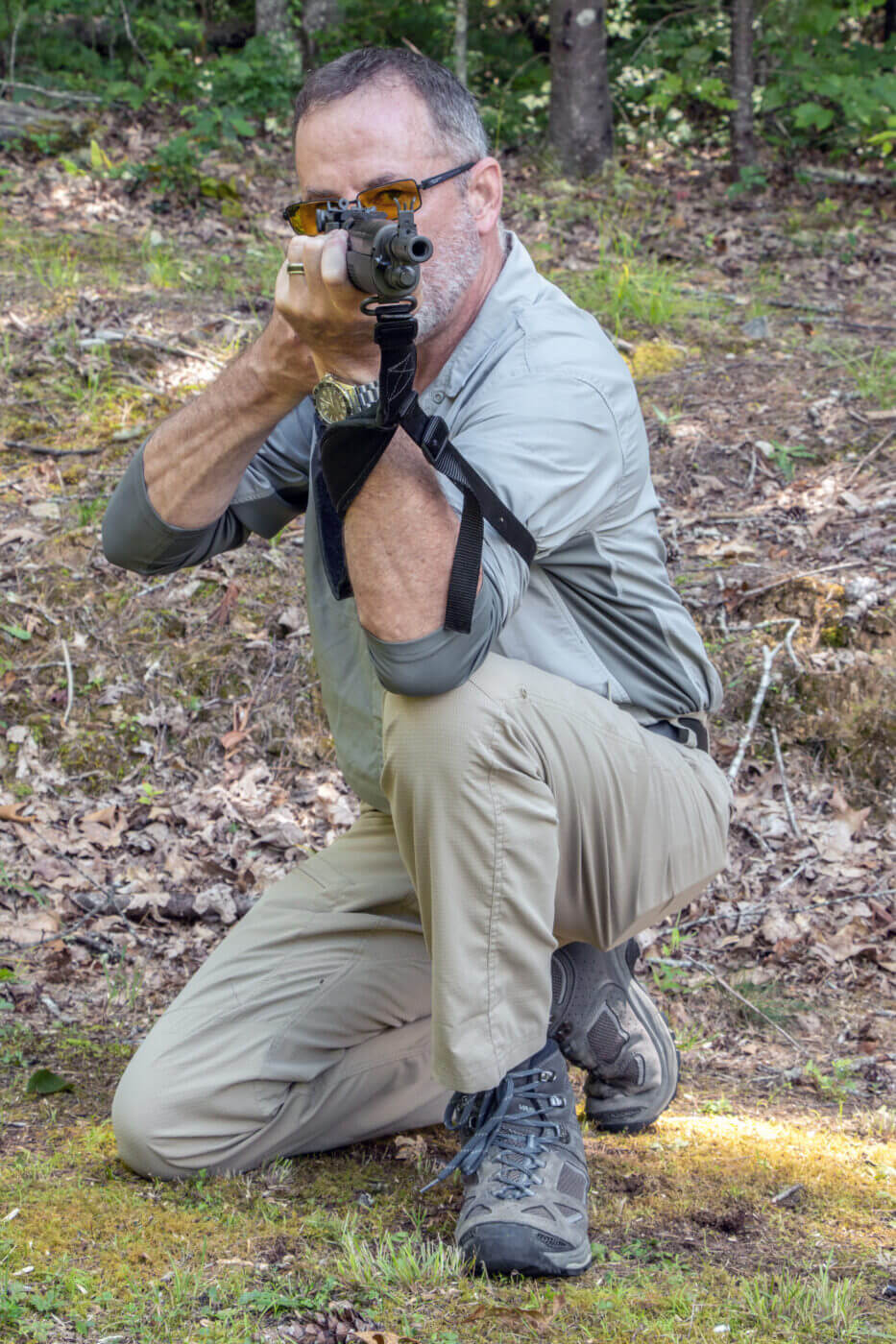 Man instructs how to shoot a rifle from a kneeling position