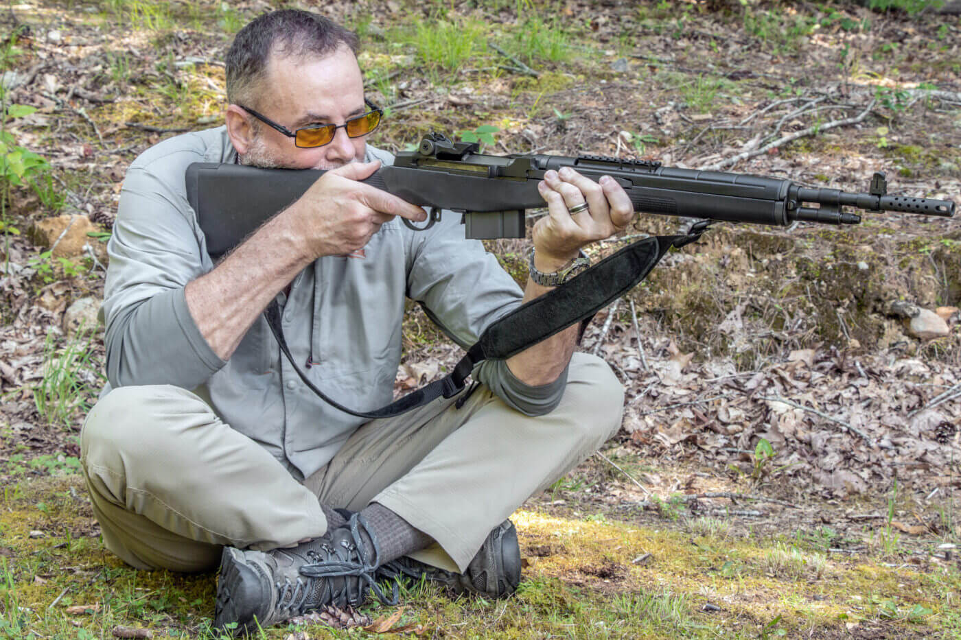 Man demonstrates how to shoot a rifle while sitting