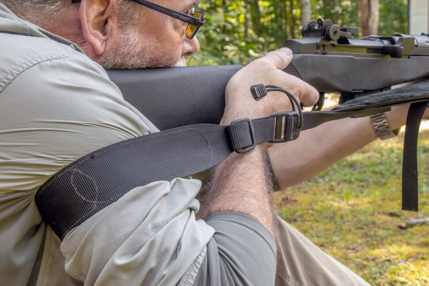 Man teaching how to use a sling while shooting a rifle from a sitting position