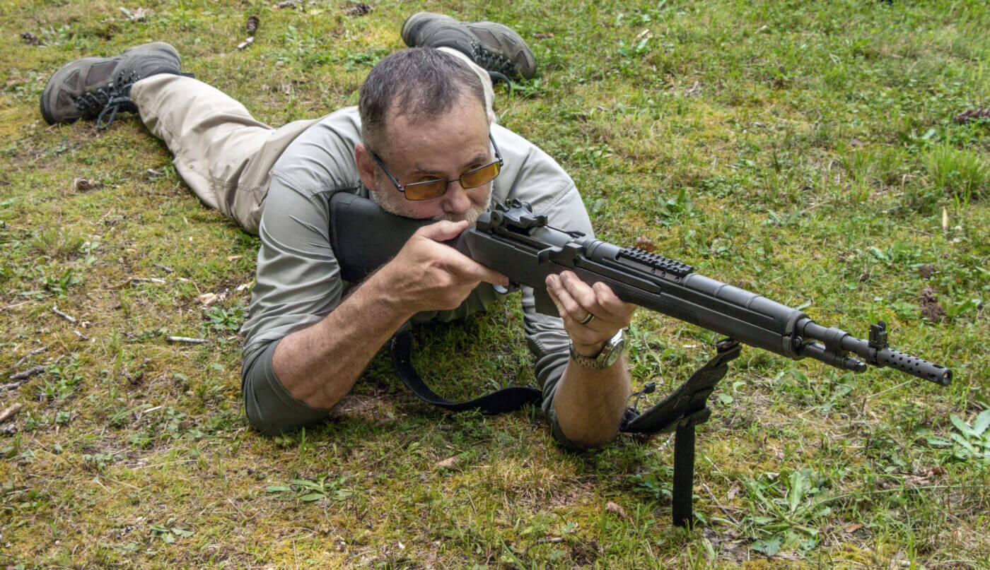 Instructor demonstrates shooting a rifle from a prone position