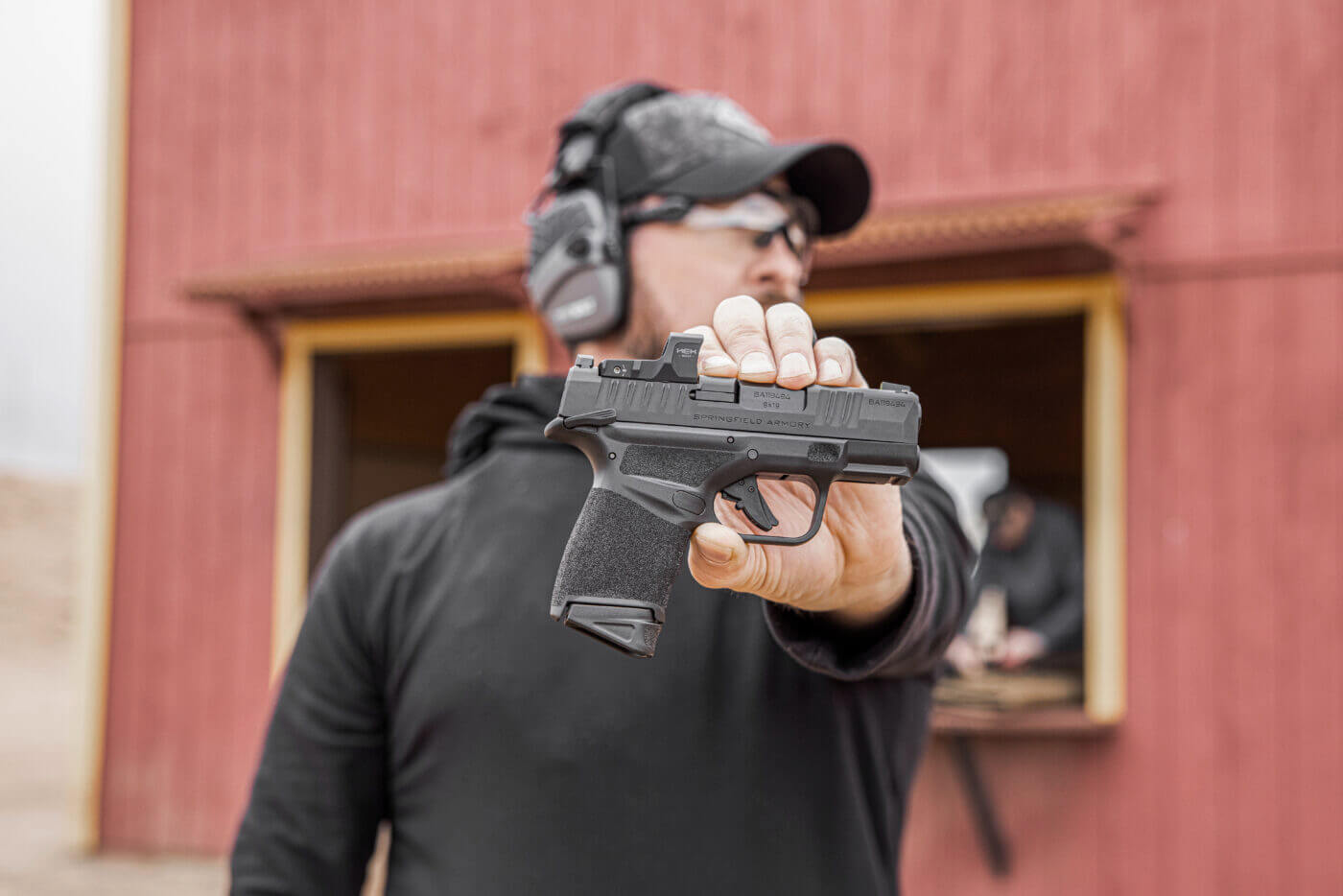 Holding a Springfield Hellcat pistol in front of building