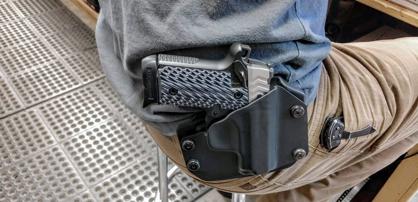 Person seated with Springfield 911 pistol in holster