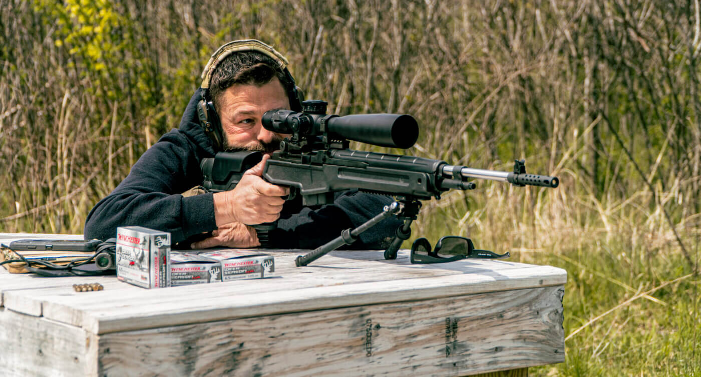 Man shooting a rifle while focusing on the reticle