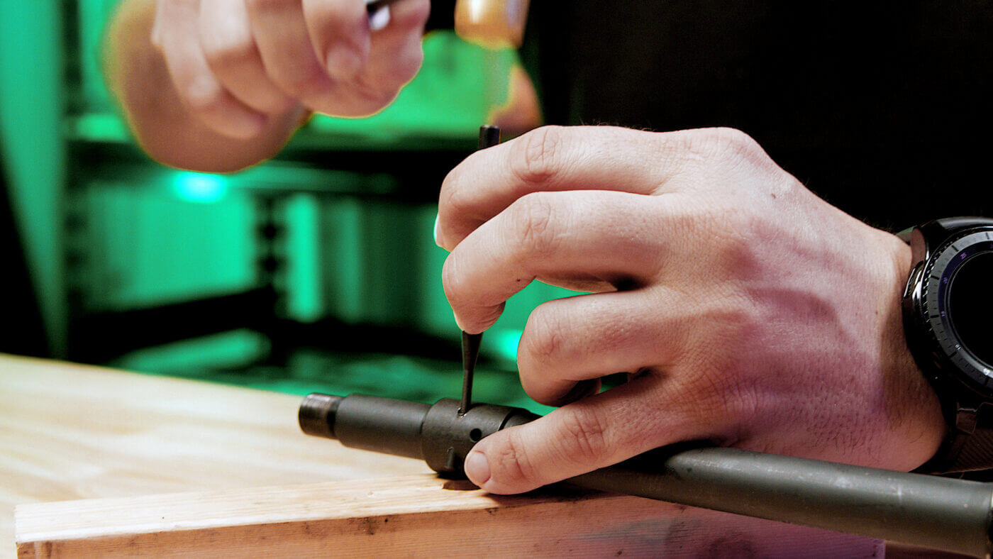 Man removing the pin on a gas block on an AR-15 pistol