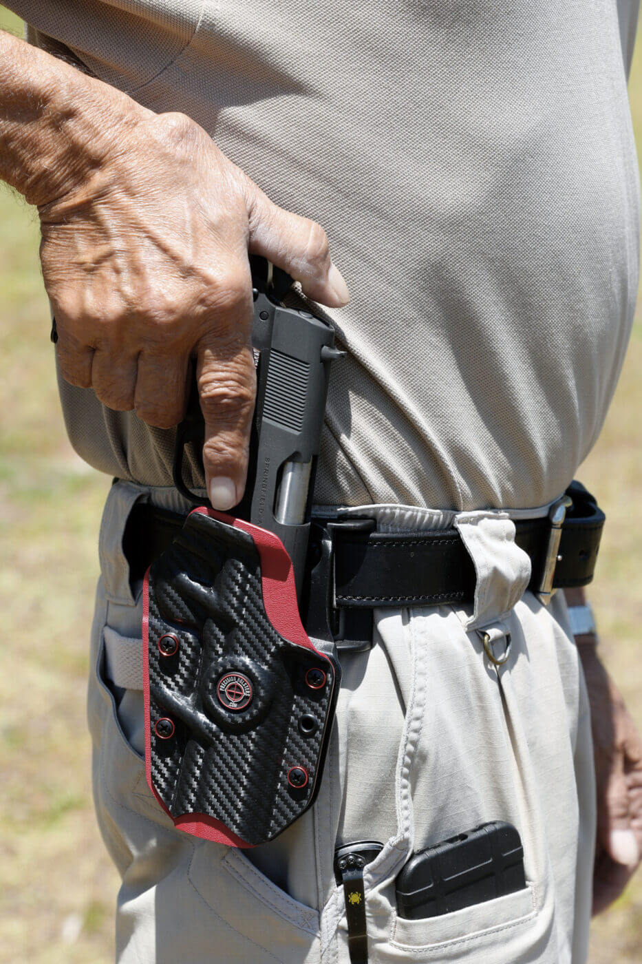 Man holstering the 1911 with a thumb hold