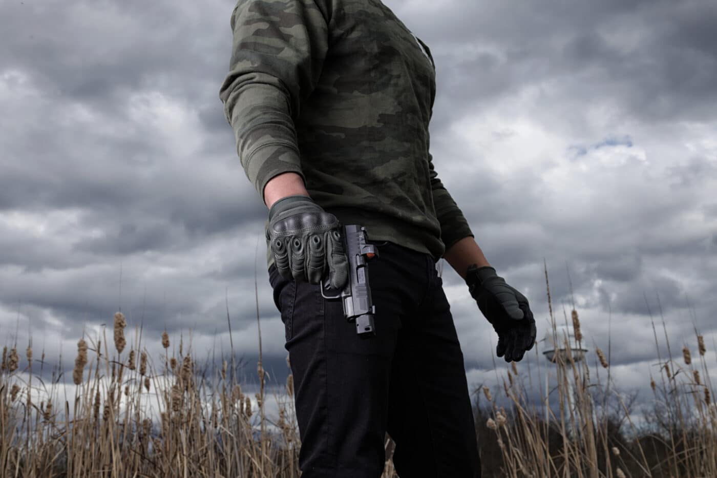 Man in gloves holding  a Springfield Armory Hellcat with HEX Wasp optic mounted