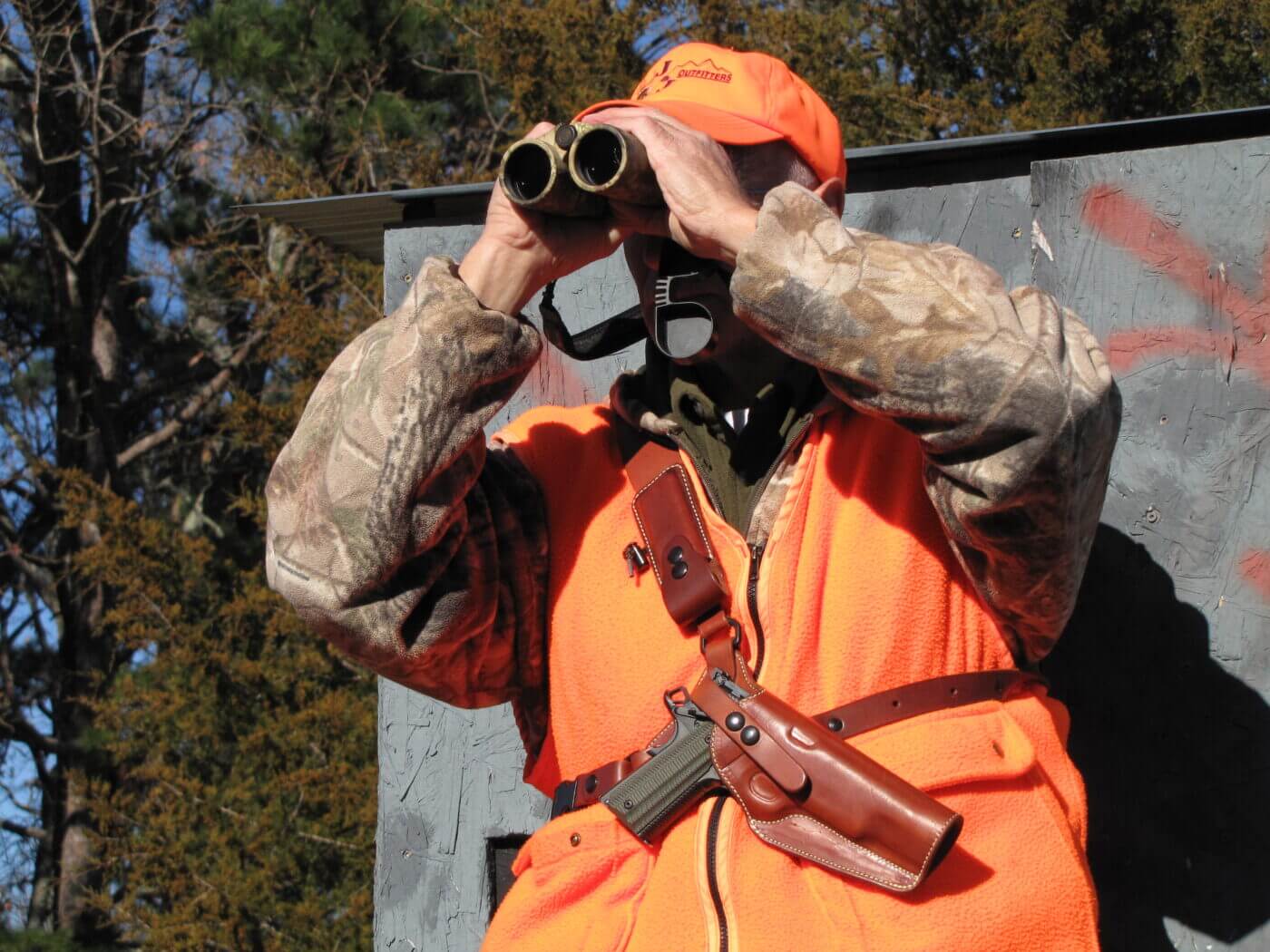 Hunter using binoculars and a chest holster with pistol