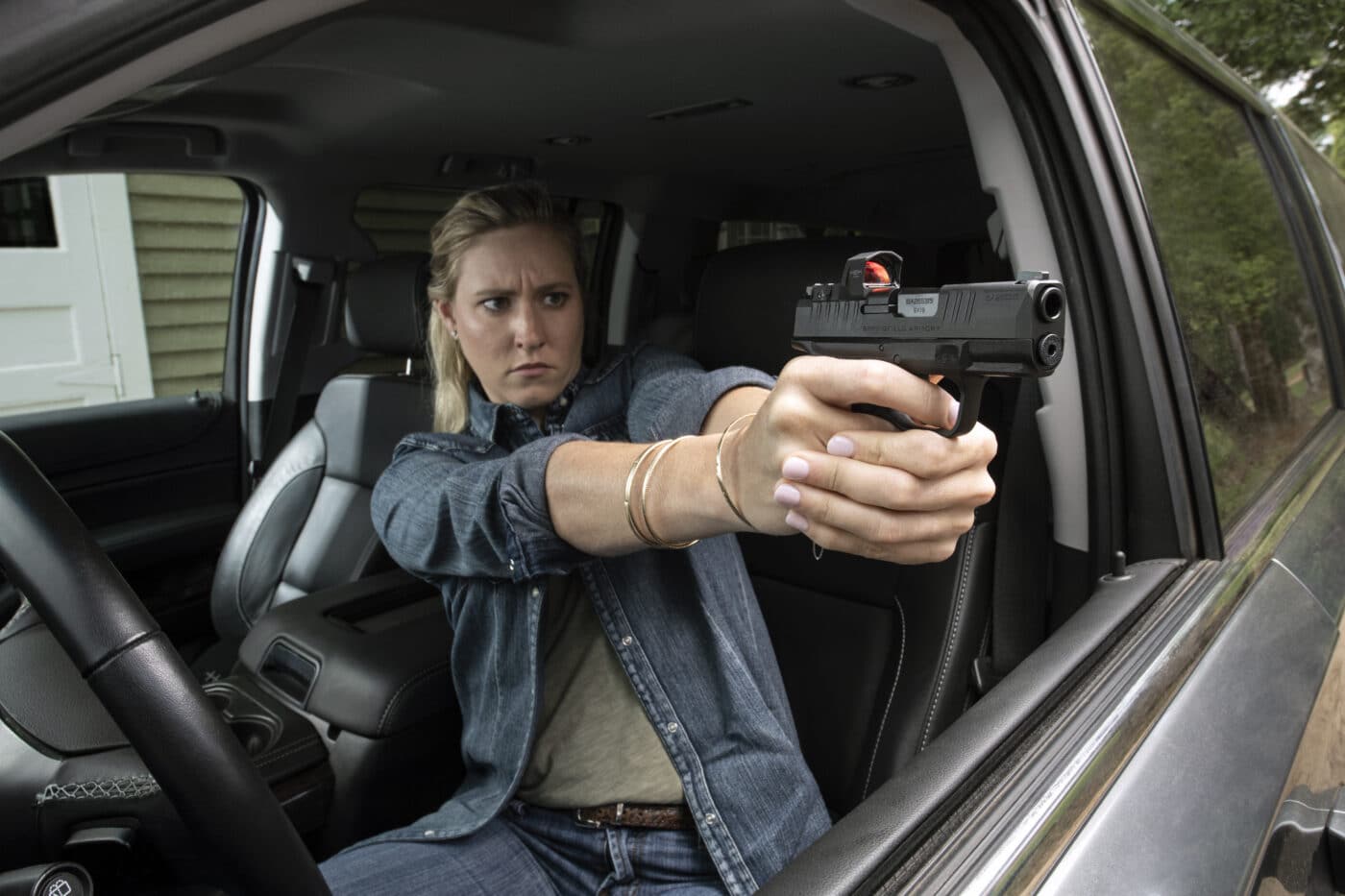 Woman shooting a pistol from inside a truck
