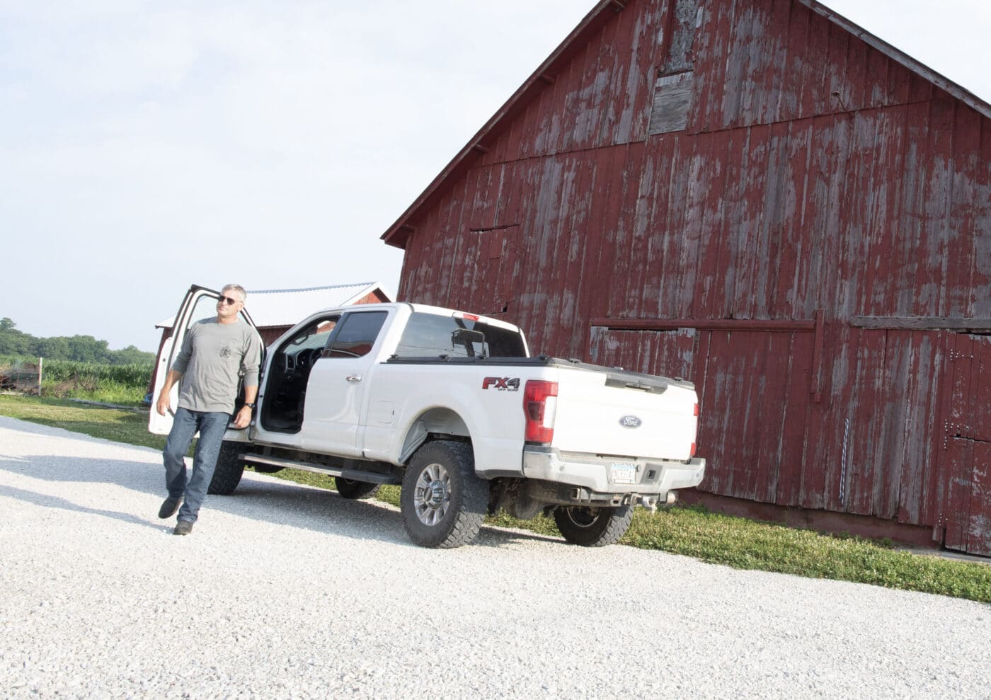 Man on farm property with truck and barn