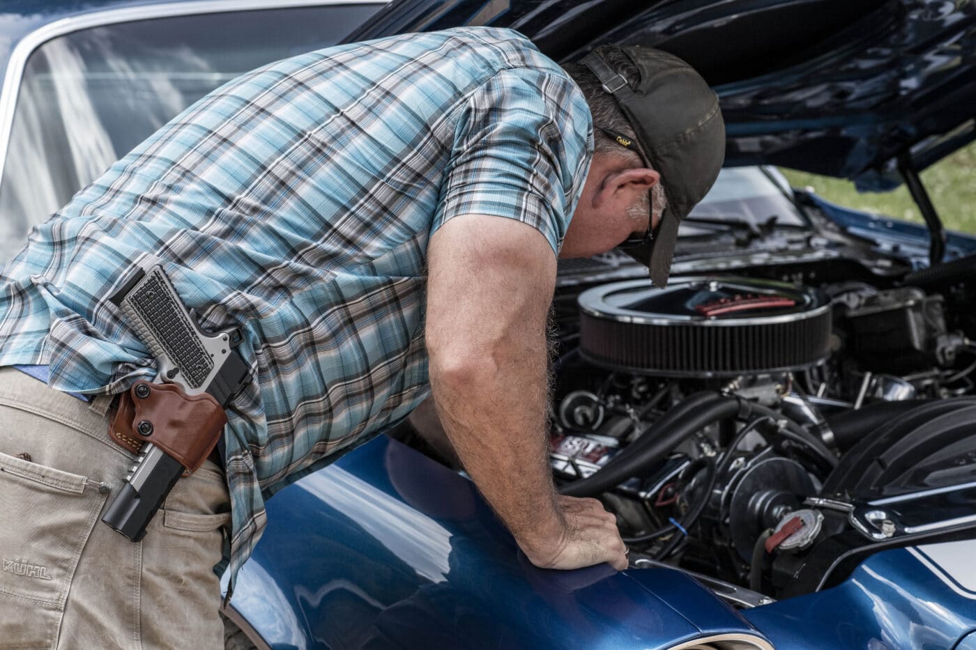 Man working on car while carrying an Emissary 1911 in a Yaqui slide holster