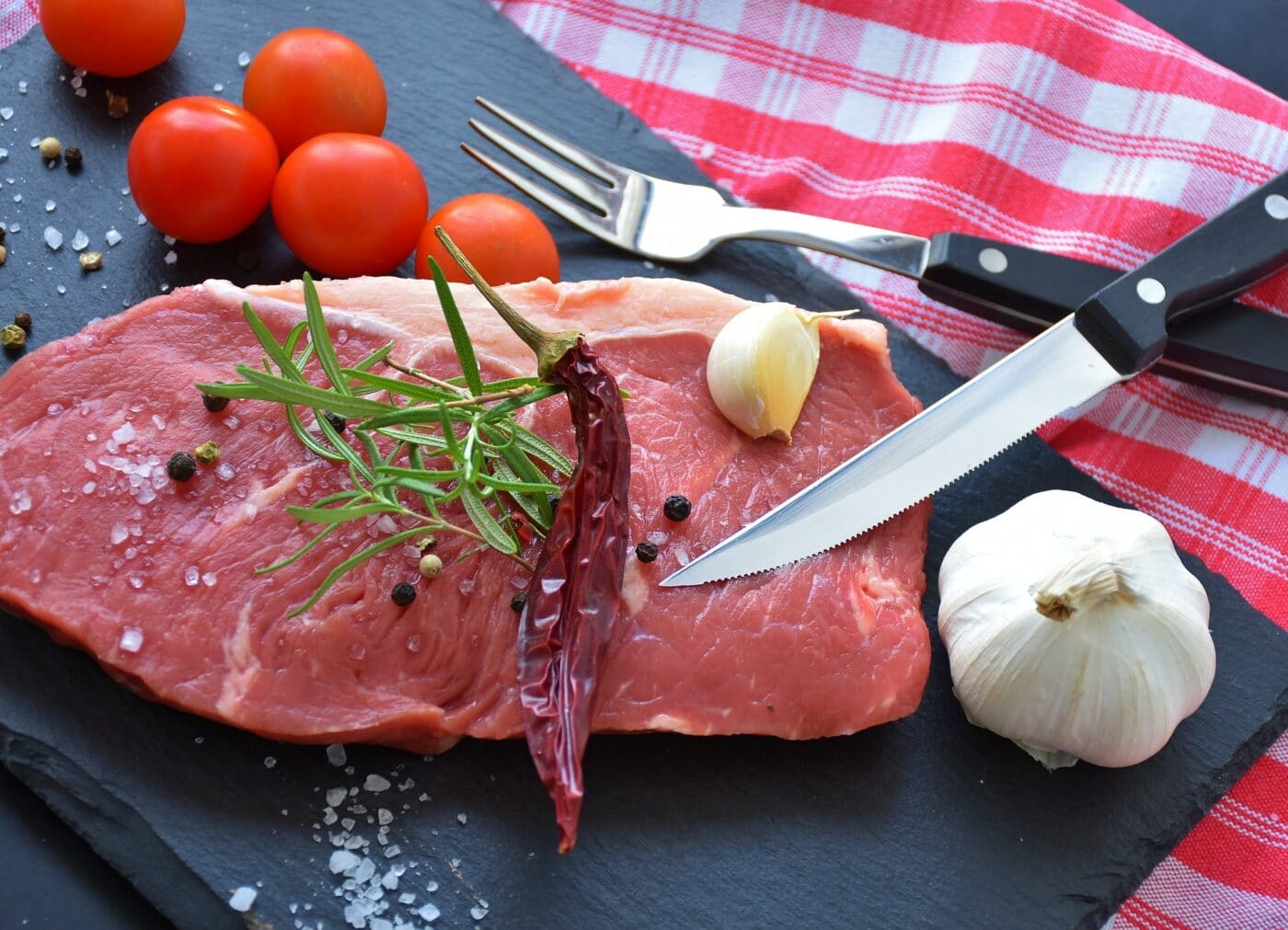 Home processed meat with knife, fork, and herbs