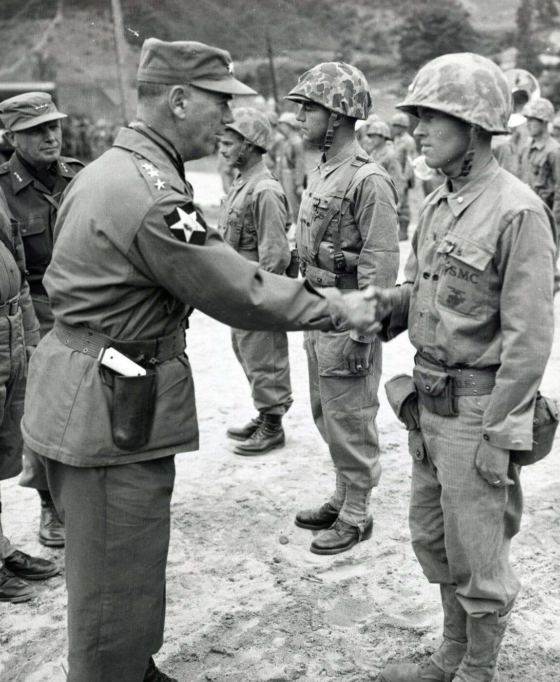 Lieutenant General James Van Fleet shakes hands with a soldier in the Korean War while carrying a 1911 pistol