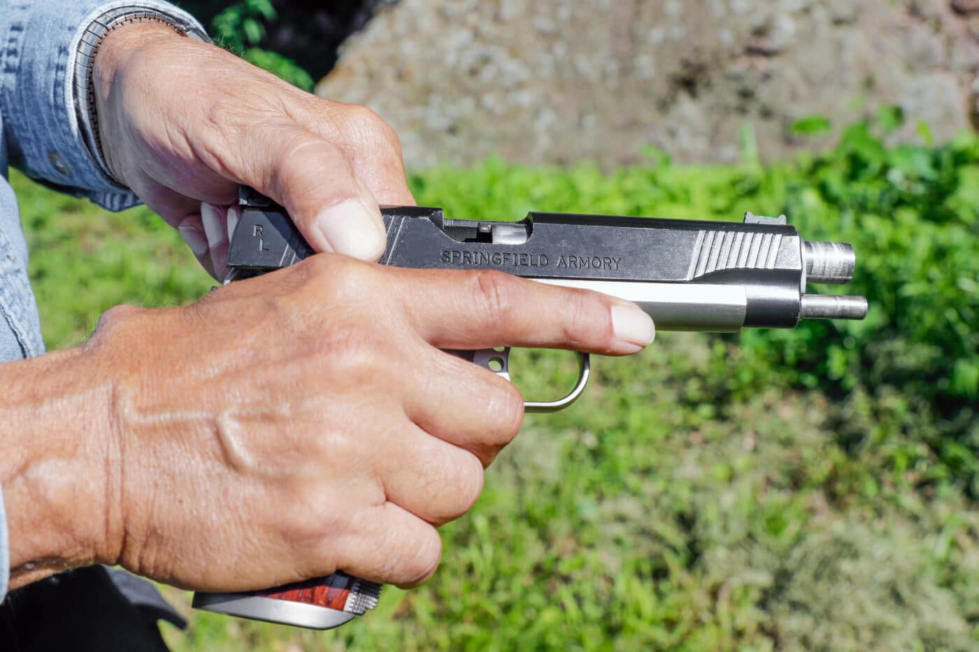 Man demonstrating chamber check on 1911 pistol