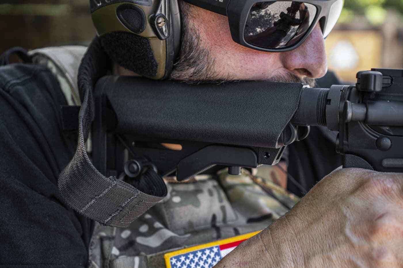 Man holding rifle and showing the attachment location of sling