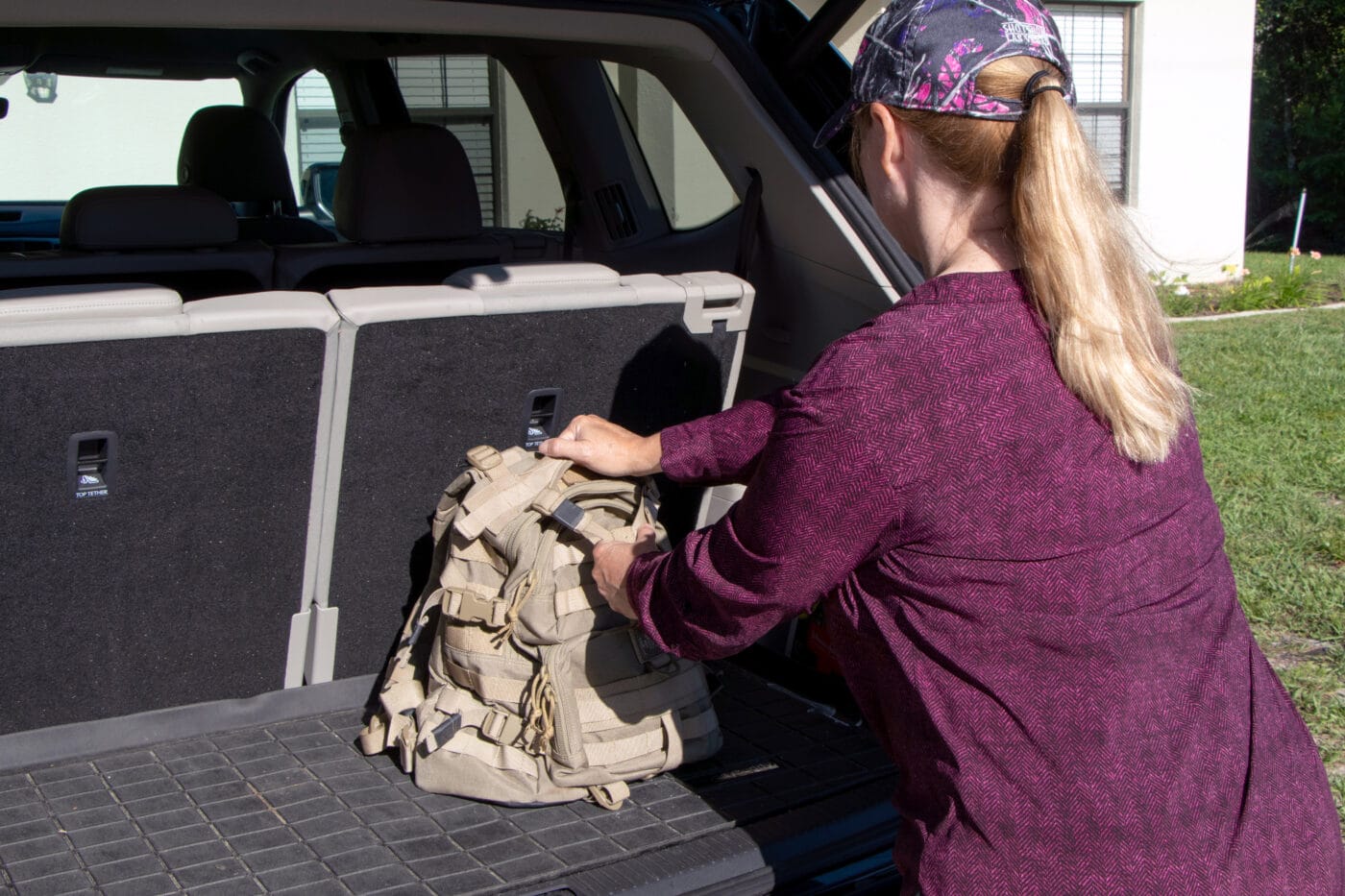 Woman placing get home bag in back of a vehicle