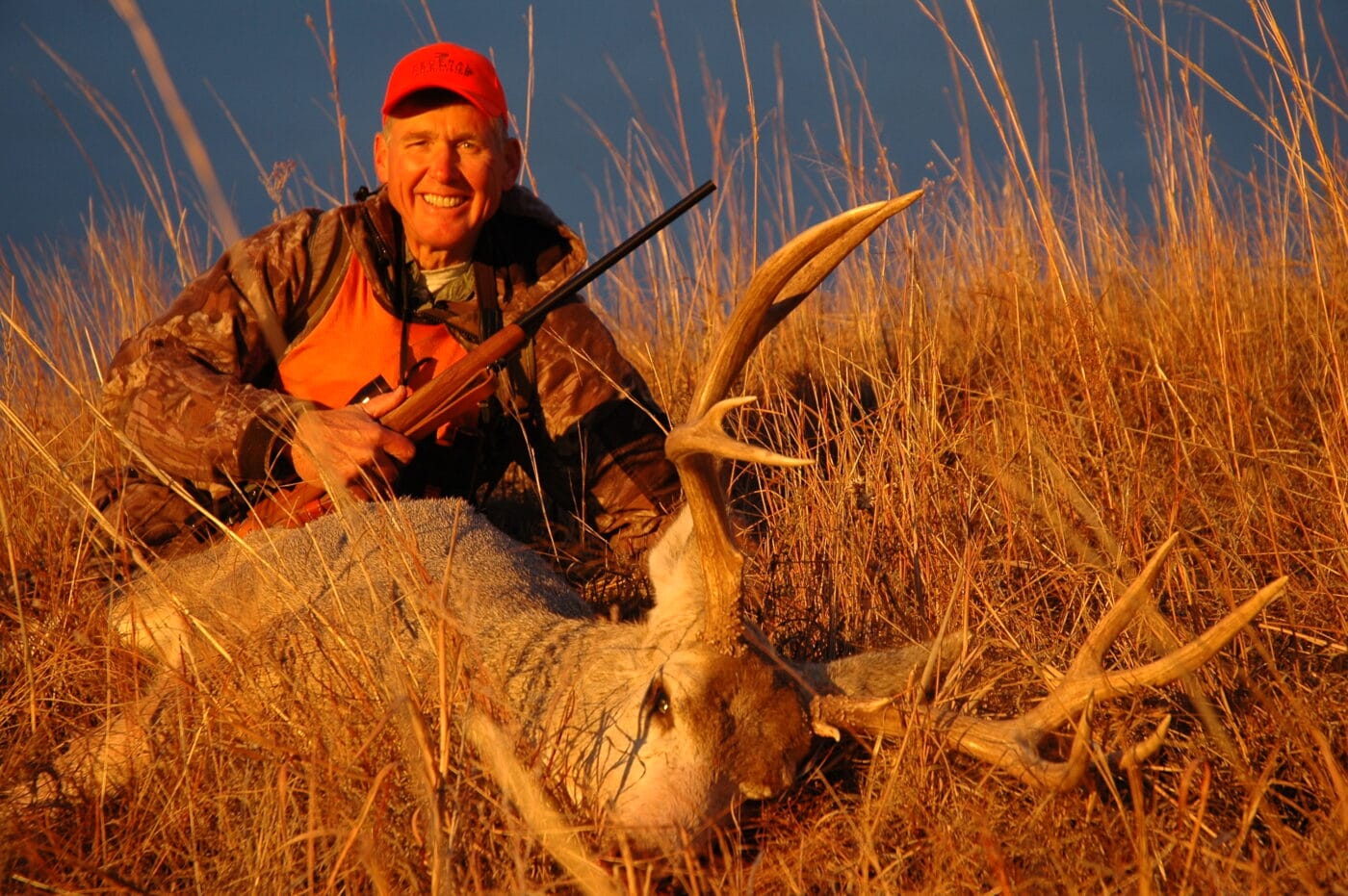 Deer hunter with buck at sunset