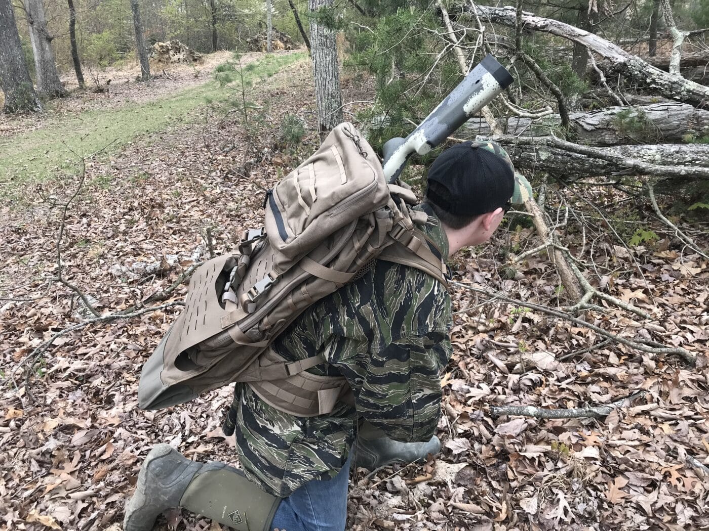 Man carrying a rifle in the Eberlestock Gunslinger II backpack