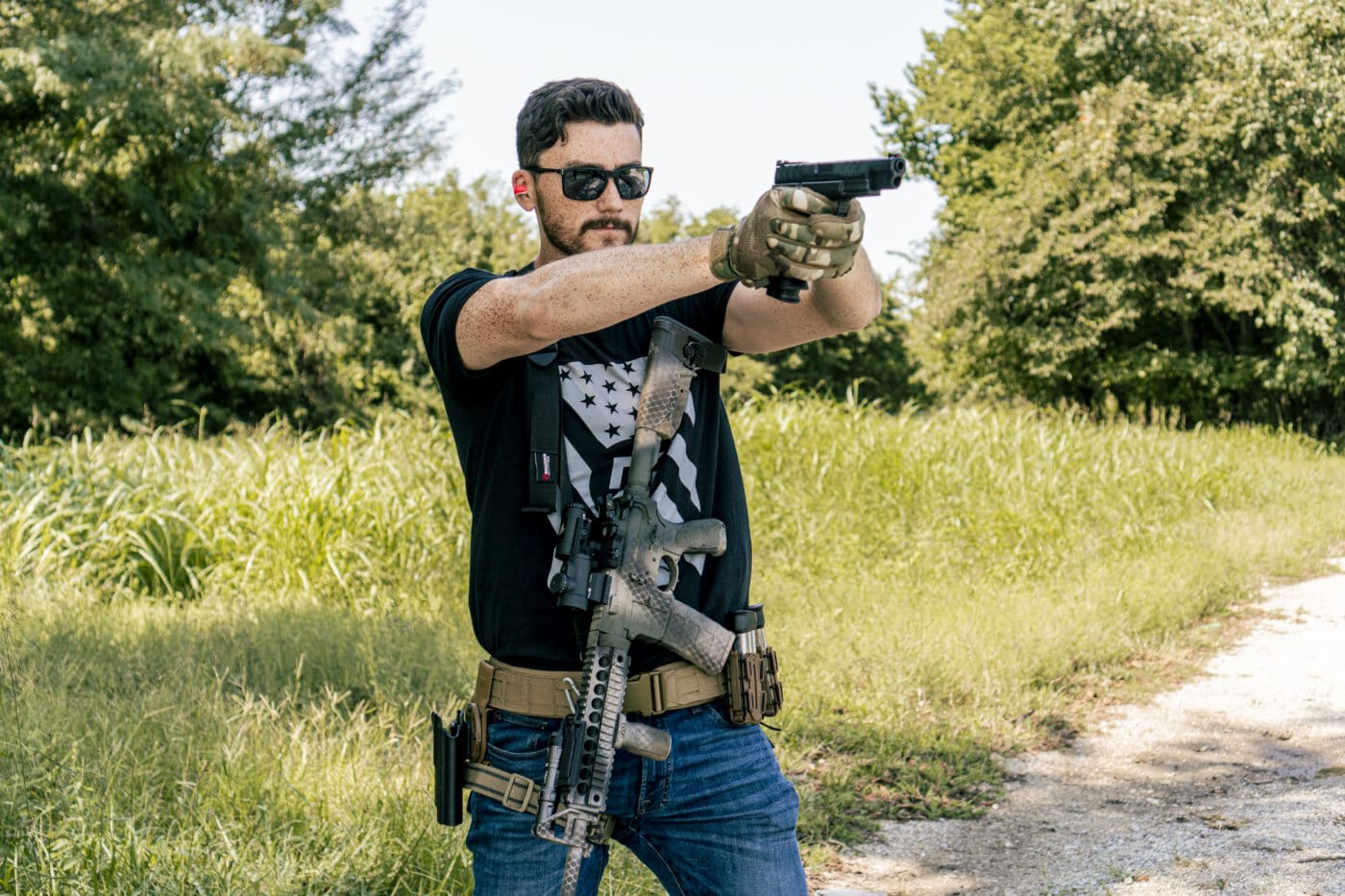 Man shooting a pistol while carrying rifle with a properly fitted sling