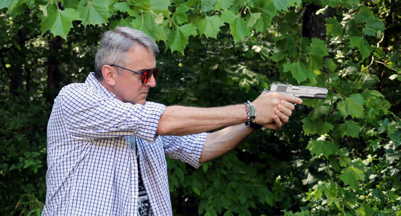 Man shooting a stainless steel 1911 pistol